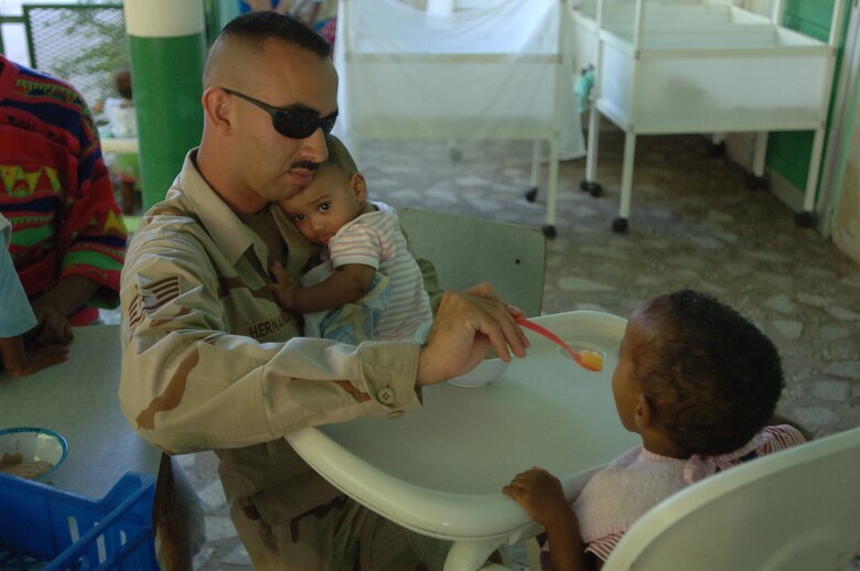 DJIBOUTI – Air Force Staff Sgt. Francisco Hernandez holds one baby while feeding another during a visit to the Djibouti baby orphanage near Camp Lemonier, Djibouti. Hernandez, a Merkel, Texas, native, is the Combined Joint Task Force-Horn of Africa Information Management Office Data Systems noncommissioned officer in charge. Servicemembers supporting the CJTF-HOA mission donate their time three times a week to help French nuns who run the facility feed the babies. More than 60 babies and toddlers are cared for at the orphanage. (U.S. Air Force photo/Staff Sgt. Jennifer Redente)