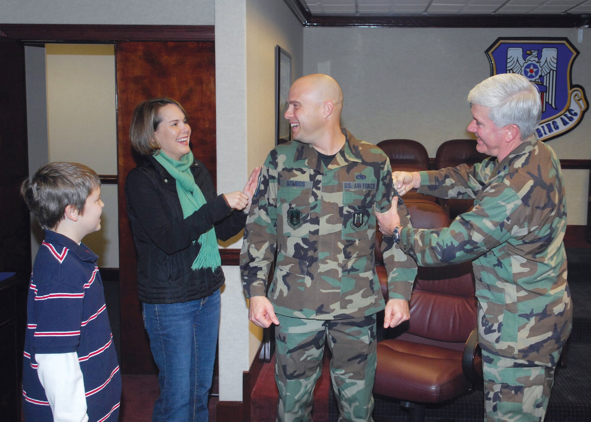 Maj. Gen Tom Owen (far right), WR-ALC commander, "tags on" Master Sgt. Jeff Gombos's new stripes during a surprising Stripes for Exceptional Performance promotion ceremony Jan. 7, as wife, Jen, and son, Kevin, look on. The newly striped master sergeant is an enlisted aide to the Center commander. U. S. Air Force photo by Claude Lazzara
