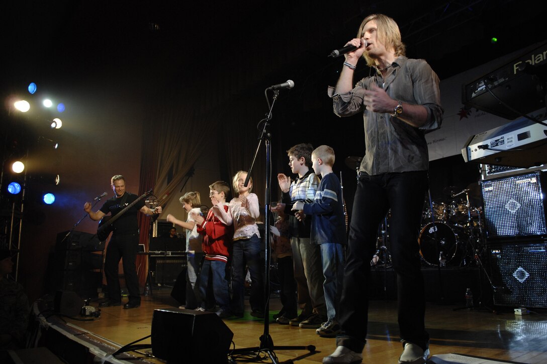 Gary Sinise and Jeff Vezain, members of the Lt. Dan Band, sing and dance on stage with children from the crowd during the United Service Organizations entertainment tour at Ellsworth Air Force Base, S.D., Feb. 1, 2008. The private concert for U.S. troops is the first this year in the series of stateside USO tours.(U.S. Air Force photo By Senior Airmen Angela Ruiz) 
