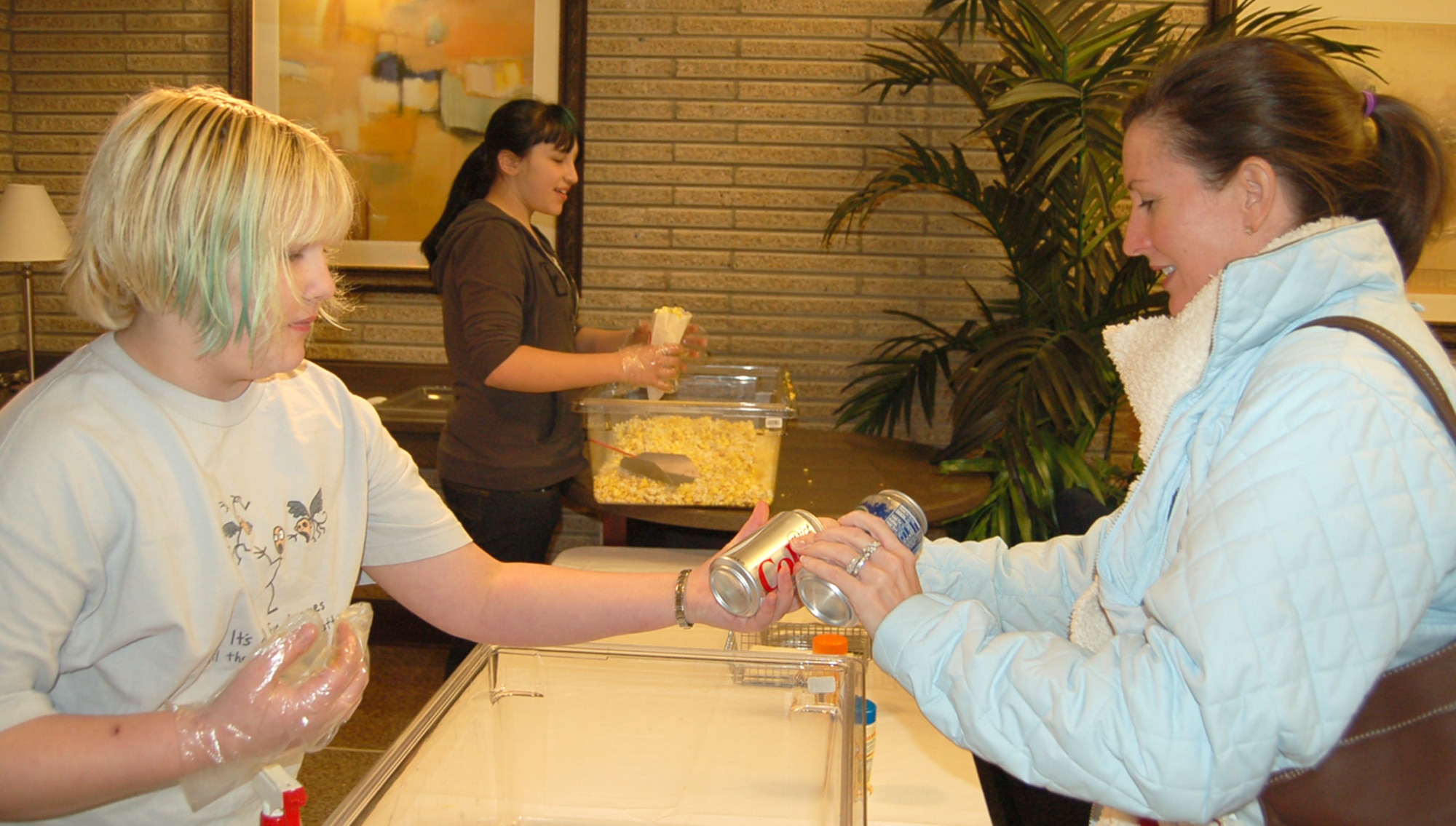 Rachel Trent, from the Peterson Youth Center, hands popcorn and soda to Mrs. Nancy Diel Feb. 1 during free movie nights at the base theater. Sponsored by the 21st Services Squadron, members with access to the base can enjoy free, newly-released movies and discounted snacks and beverages each week. Mrs. Diel is married to Lt. Col. Todd Diel who is assigned to Air Force Space Command. (U.S. Air Force photo/Corey Dahl)