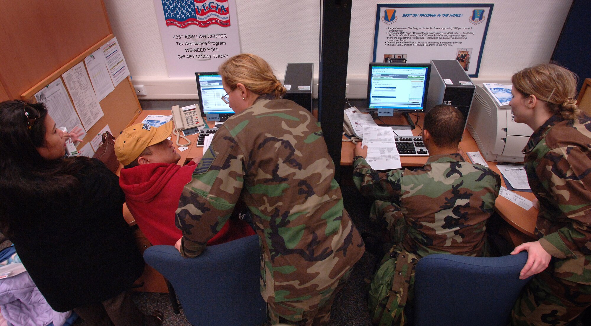 Master Sgt. Mikaela Grogg (left) assists Army Corporal Michael Edillor and his wife, Theresa, while Capt. Mary Ellen Payne assists Airman 1st Class Donovan Barnes, at the tax office at Ramstein Air Base, Germany, Feb. 4. Sergeant Grogg is a volunteer tax assistant assigned to the 435th Mission Support Squadron and Captain Payne is the officer In charge of the Tax Office. (U.S. Air Force photo/Master Sgt. Scott Wagers) 