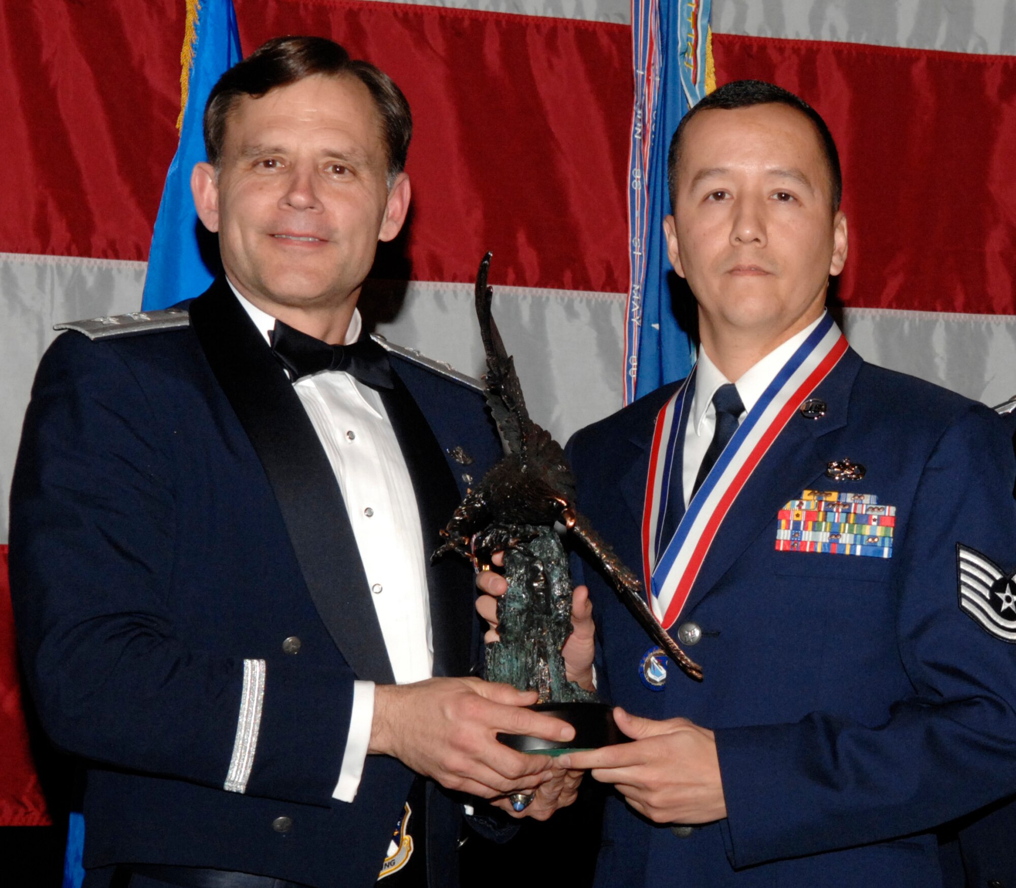 Tech. Sgt. Gene Sing, 16th Electronic Warfare Squadron, won the 53d Wing NCO of the Year Award  during the annual awards banquet Jan. 31 at the Emerald Coast Conference Center.  The night’s guest speaker and former 53d commander, Maj. Gen. (Retired) Jack Catton (left) presented the awards.  U.S. Air Force photo.