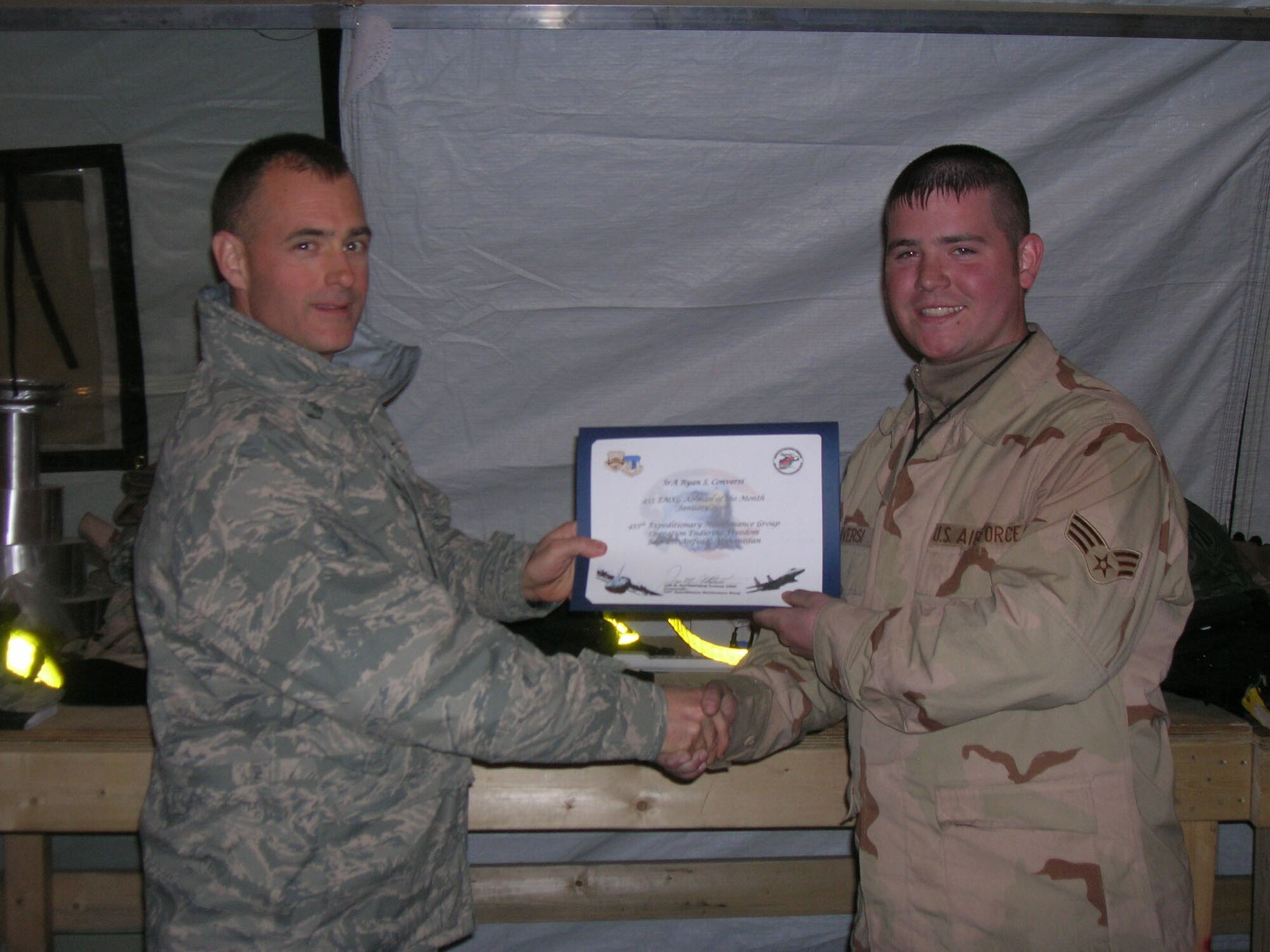 BAGRAM AIR BASE, Afghanistan -- Col. Jon Sutterfield, 455th Expeditionary Maintenance Group commander, presents Senior Airman Ryan Conversi, 455th Expeditionary Aircraft Maintenance Unit, a certificate for being named the 455th Air Expeditionary Wing airman for the month of January. Airman Conversi is deployed from Spangdahlem Air Base, Germany. (U.S. Air Force photo/1st Lt. Nicholas Bosiak)