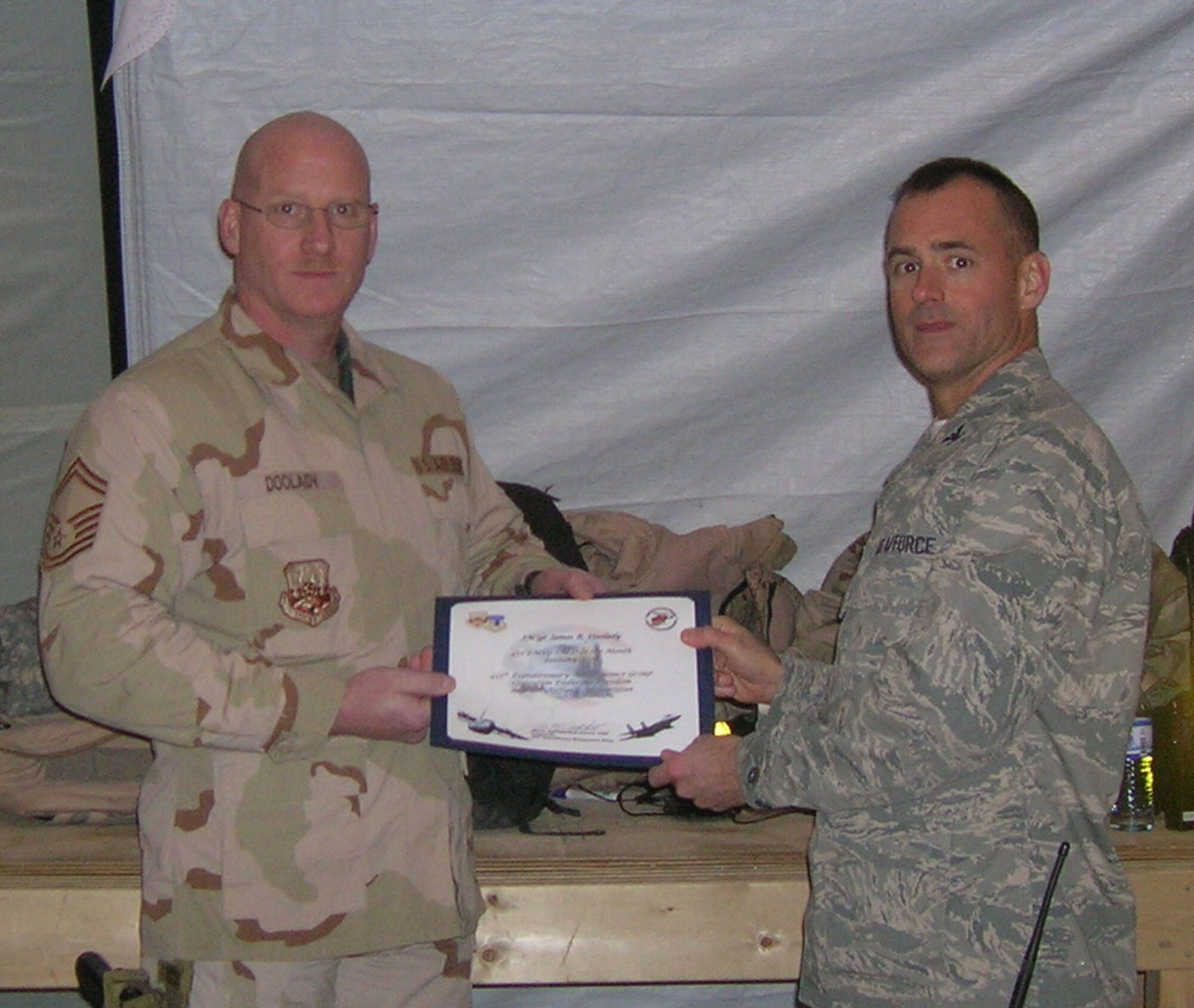 BAGRAM AIR BASE, Afghanistan -- Col. Jon Sutterfield, 455th Expeditionary Maintenance Group commander, presents Senior Master Sgt. James Doolady, 455th Expeditionary Aircraft Maintenance Unit, a certificate for being named the 455th Air Expeditionary Wing senior noncommissioned officer for the month of January. Sergeant Doolady is deployed from Spangdahlem Air Base, Germany. (U.S. Air Force photo/1st Lt. Nicholas Bosiak)