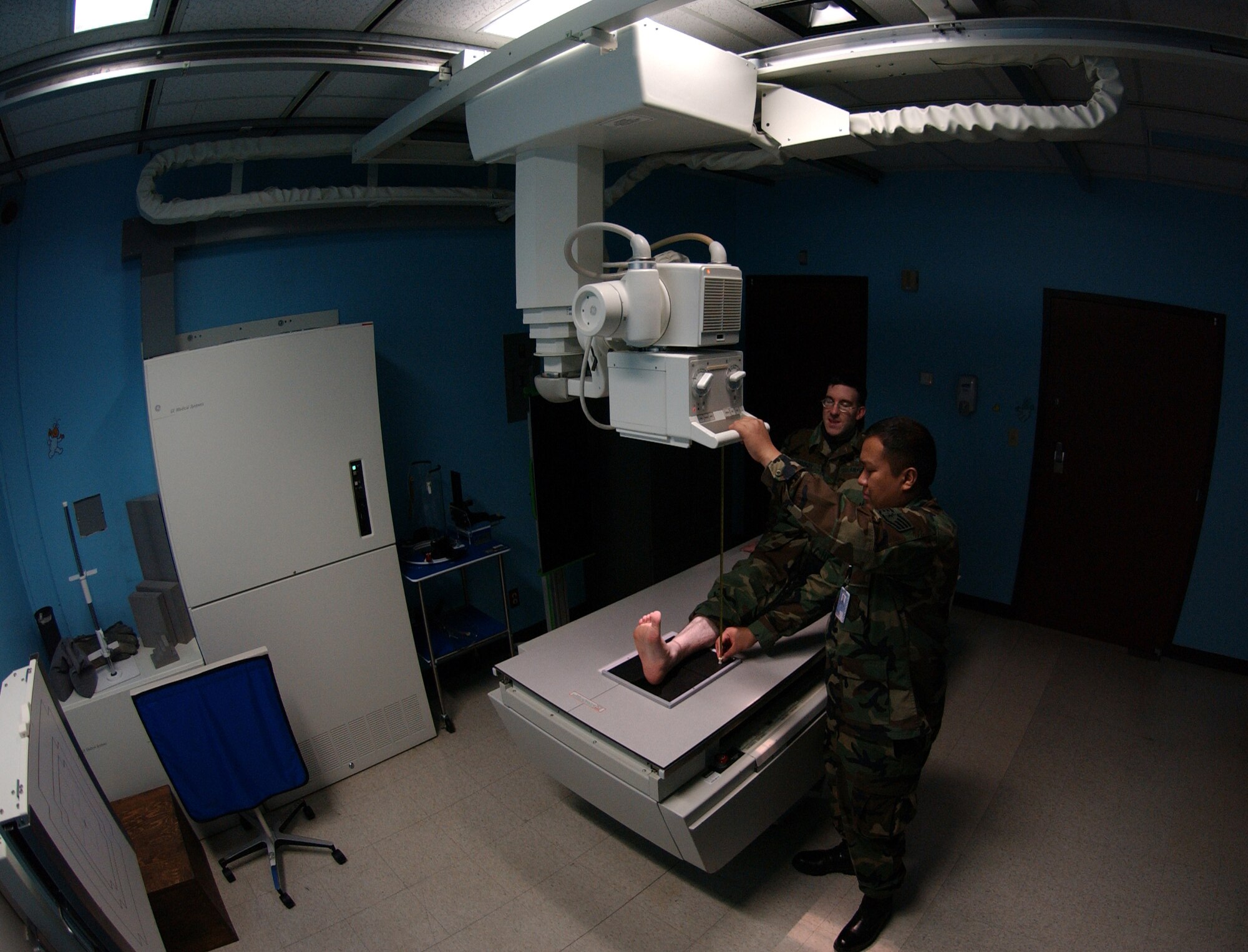 Diagnostic Imaging Technicians'  U.S Air Force Staff Sgt Rutherford Alejo (right) and Staff Sgt Joseph Moody (center) demonstrates how a patient with a possible ankle sprain or fracture is positioned and the proper distance is set between the injured area and the x-ray machine before the area of concern is x-rayed using the anterior- posterior exposure here at Eielson Air Force Base, Alaska on Feb 5, 2008. The anterior-posterior x-ray exposure means the x-rays will pass through the patient from front to back.

(U.S Air Force photo by: Staff Sgt Eric T. Sheler)