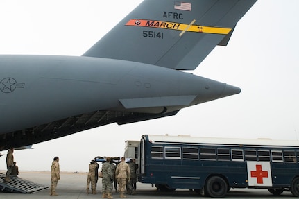 BALAD AIR BASE, Iraq -- Members of the 332nd Contingency Aeromedical Staging Facility and volunteers, offload patients from a transport bus to a C-17 Globemaster III here, Jan. 1. The aircraft was reconfigured to support the transportation of patients, medical equipment and flight medical professionals to safely transport patients outside of the combat zone. (U.S. Air Force photo/ Staff Sgt. Joshua Garcia)