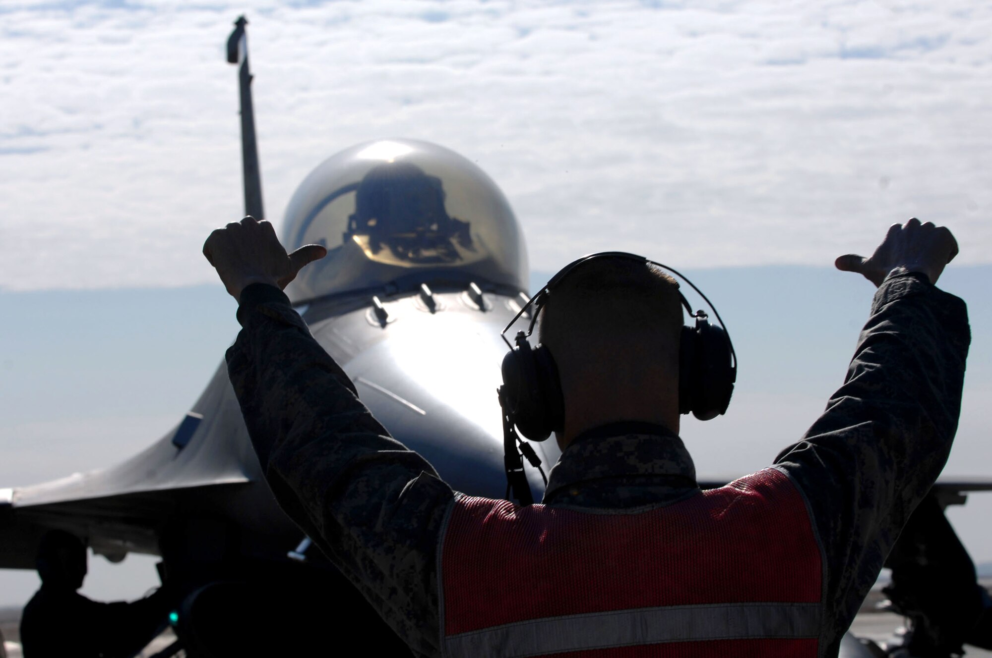 Air Force Staff Sgt. Jeremy Lewis, a crew chief with the 332nd Expeditionary Aircraft Maintenance Unit, gives a signal to Capt. Travis Keenan, a pilot with the 22nd Fighter Squadron pilot, before de-arming his F-16 Fighting Falcon aircraft at Balad Air Base, Iraq. (U.S. Air Force photo/Senior Airman Julianne Showalter) 