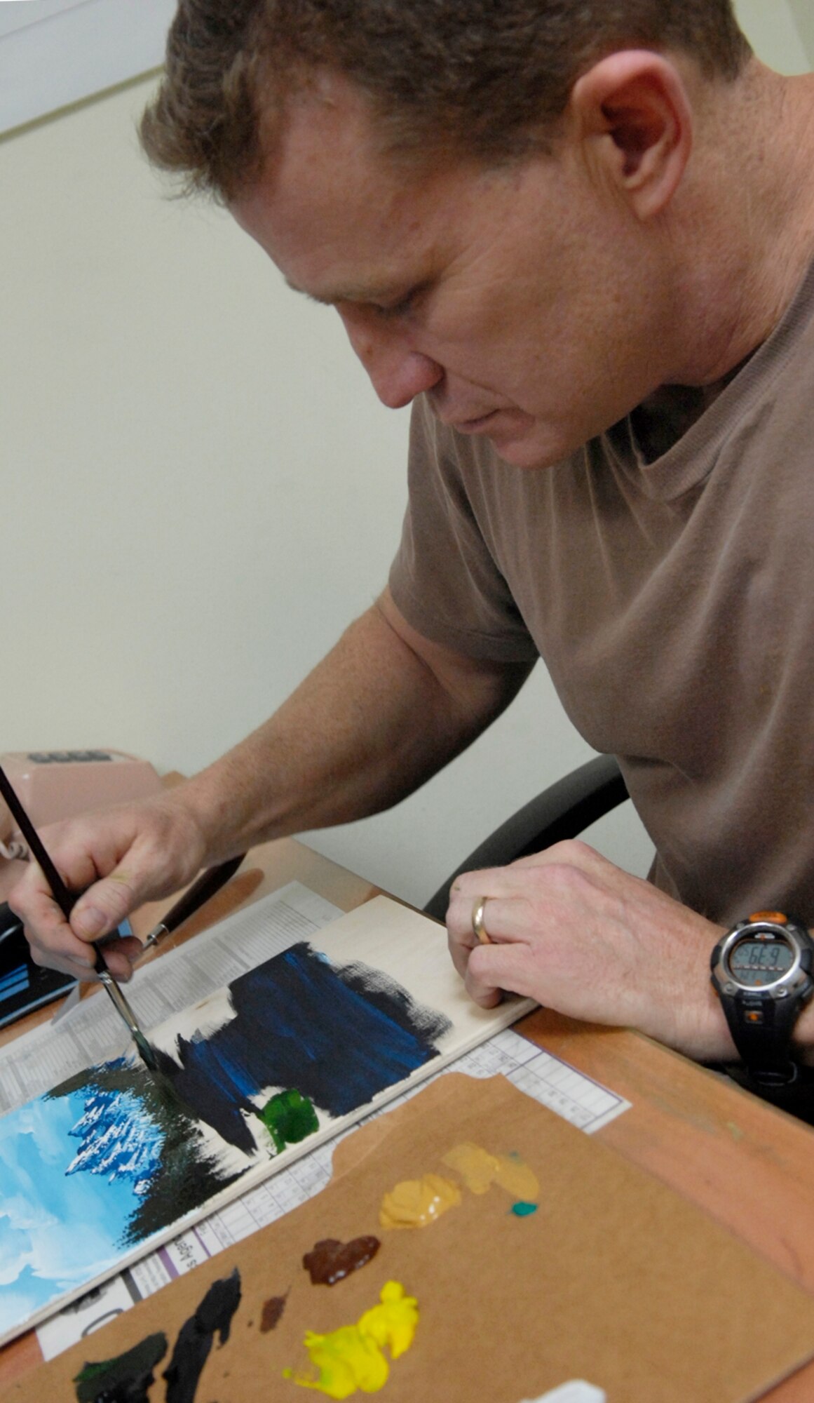 Tech. Sgt. Robert Sommers, 376th Expeditionary Civil Engineer Squadron, adds details to his painting.  Sergeant Sommers sells the paintings he creates from leftover wood scraps and donates the proceeds to a local heart foundation that helps pay for heart surgeries for children whose parents are unable to pay for the surgeries themselves.  (Air Force photo by Senior Airman Tabitha Kuykendall)
