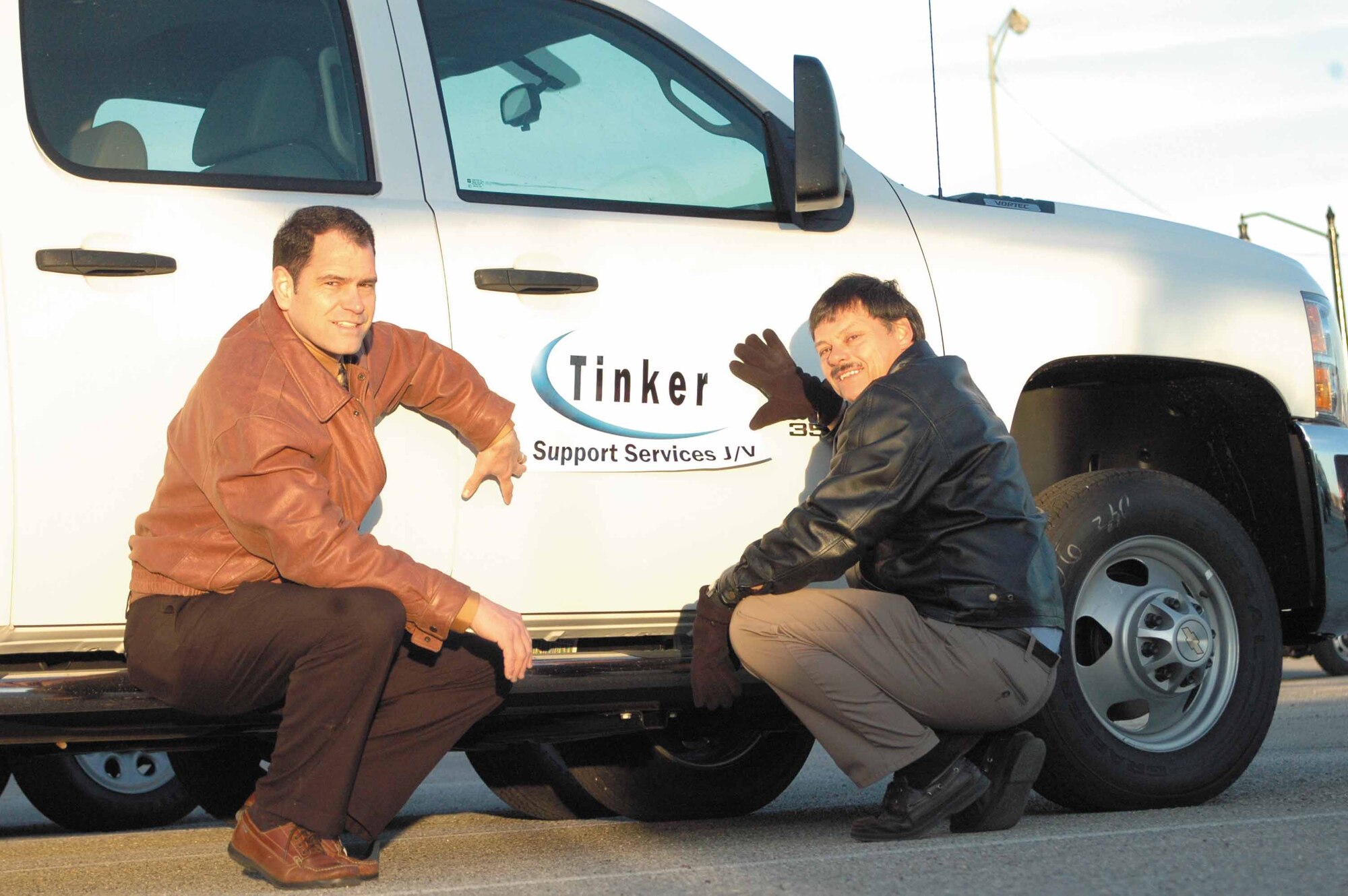 Matt DeToy, civil engineer quality assurance officer and Richard Wadhams, Tinker Support Services project manager from Chugach Alaska Corporation and Alutiiq Joint Venture are sizing up the new logo on one of the more than 130 new civil engineer support vehicle customers will see transporting crews. According to Mr. Wadhams more vehicles will allow more technicians and craftsmen to get to more job sites. “We are going to increase the number of crews while simultaneously decreasing the number of hours it takes to do the job. Doing more with less,” he said.  (Air Force photo by Brion Ockenfels)
