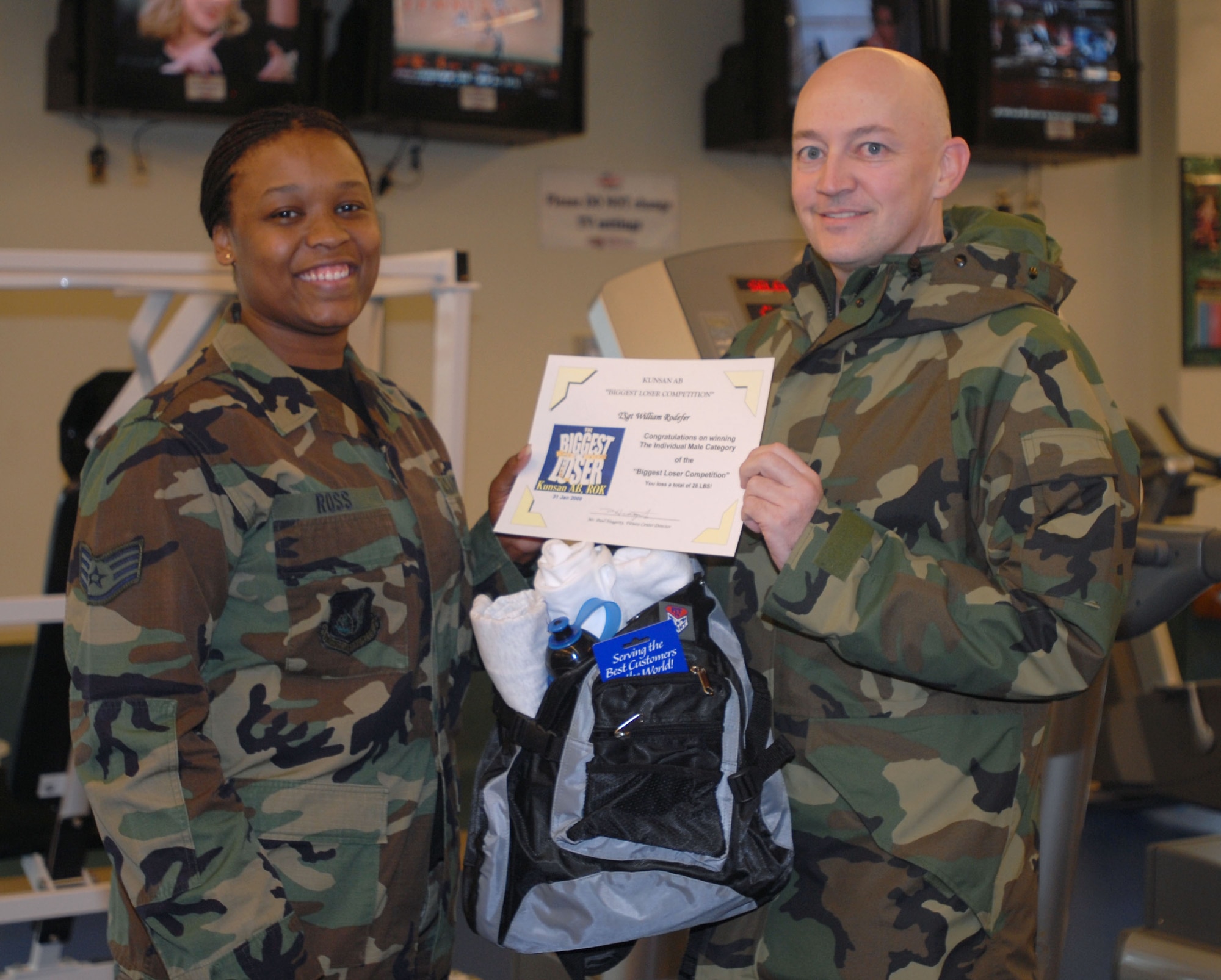 KUNSAN AIR BASE, South Korea -- Staff Sgt. Theresa Ross, special events coordinator for the 8th Services Squadron fitness center presents Tech. Sgt. William Rodefer, from the 8th Maintenance Operations Squadron's "The Losers Club" with the top male award during the Biggest Loser awards ceremony here Feb. 6.  Sergeant Rodefer achieved a personal weight-loss of 28 pounds.  The Biggest Loser competition is one of the many events that the fitness center hosts to motivate Airmen to get fit to fight and maintain a healthy Air Force lifestyle.  (U.S. Air Force photo/Staff Sgt. Darcie Ibidapo)