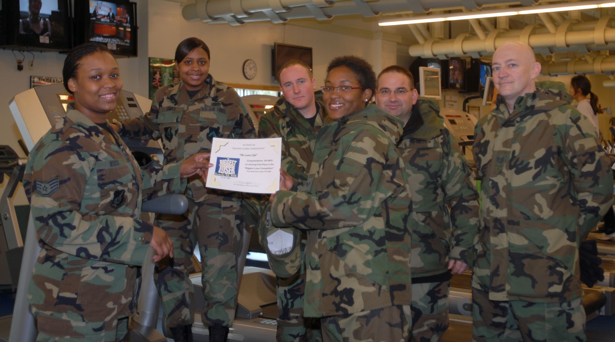 KUNSAN AIR BASE, South Korea -- Staff Sgt. Theresa Ross, special events coordinator for the 8th Services Squadron fitness center presents Staff Sgt. Andres Penn, team captain for the 8th Maintenance Operations Squadron's "The Losers Club" and her teammates with the first place award during the Biggest Loser awards ceremony here Feb. 6.  "The Losers Club" completed the competition with a team weight-loss of 74 pounds.  The Biggest Loser competition is one of the many events that the fitness center hosts to motivate Airmen to get fit to fight and maintain a healthy Air Force lifestyle.  (U.S. Air Force photo/Staff Sgt. Darcie Ibidapo)