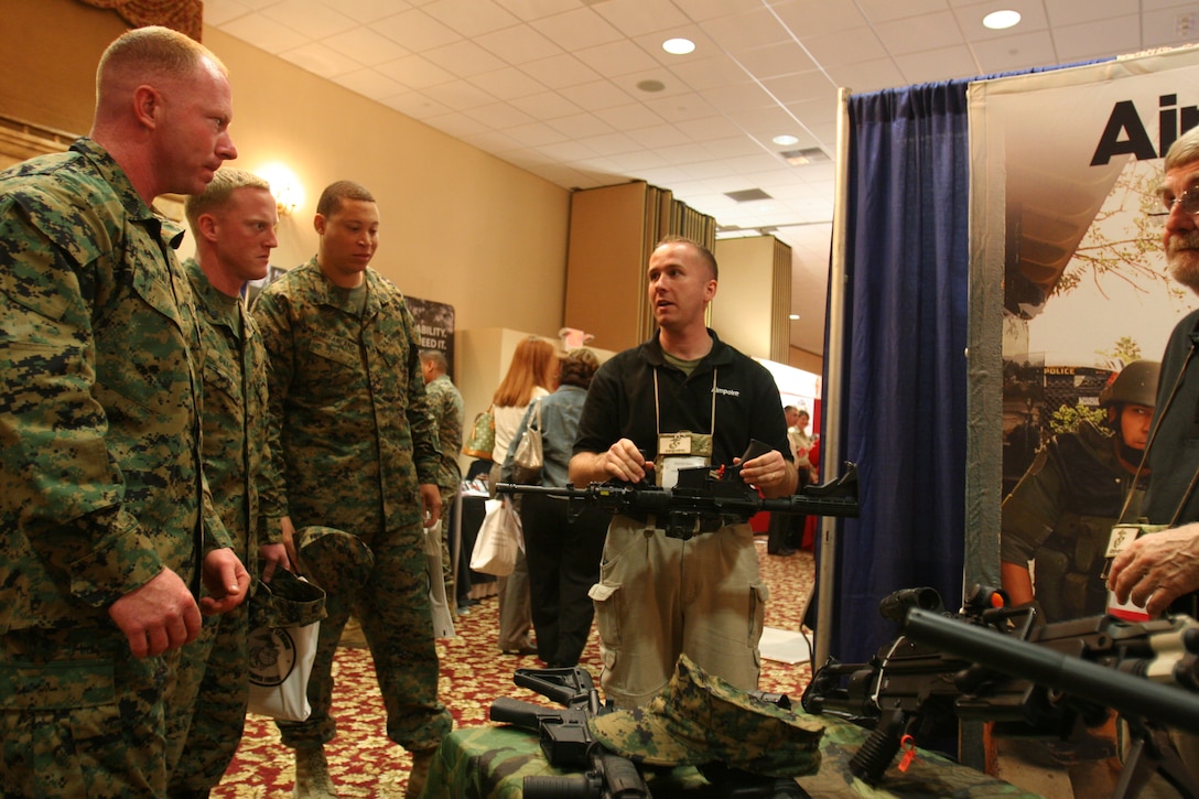 Michael McChesney, pro staffer, Aimpoint, demostrates the new scopes and their dependability to three Marines, as he is about to drop the weapon on the ground, scope facing down at. McChesney is one of many vendors who participated in the 2009 Marine Exposition West February 4 through 5 here.