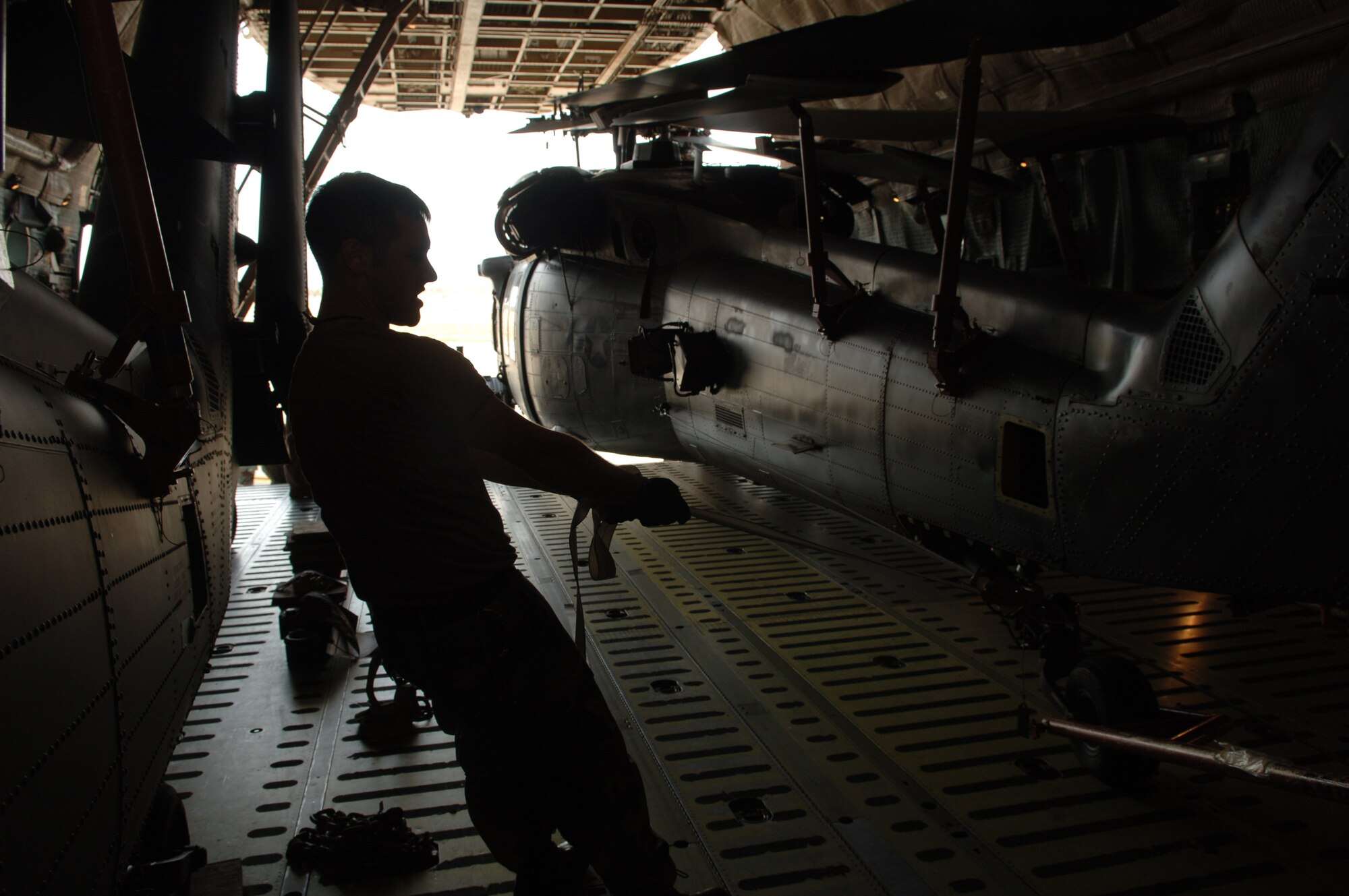 MOODY AIR FORCE BASE, Ga -- Senior Airman Jason Chavies, 723rd Aircraft Maintenance Squadron HH-60G crew chief, helps keep an HH-60G Pave Hawk from being damaged by pulling tie-down cables away from its frame during positioning here Feb. 6. SrA Chavies was helping to load an HH-60G Pave Hawk into a C-5 Galaxy for a deployment to Iraq. (U.S. Air Force photo by Senior Airmen Schelli Jones)