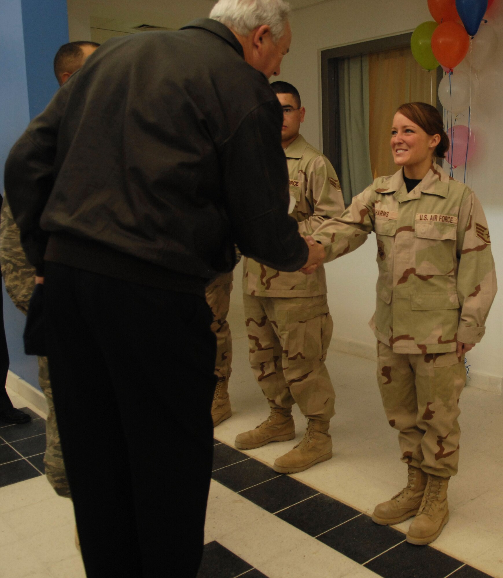One of the most junior residents to move into the new dormitories, Staff Sgt. Jennifer Harms, receives a key from Secretary of the Air Force Michael W. Wynne during the grand opening festivities of the Blatchford-Preston Complex Feb. 5 in Southwest Asia. Sergeant Harms is the NCO in charge of training at the 379th Civil Engineer Squadron, Readiness and Emergency Management section. She is deployed from the 183rd Fighter Wing, Springfield, Ill., Air National Guard. (U.S. Air Force photo/Master Sgt. Andy Dunaway) 