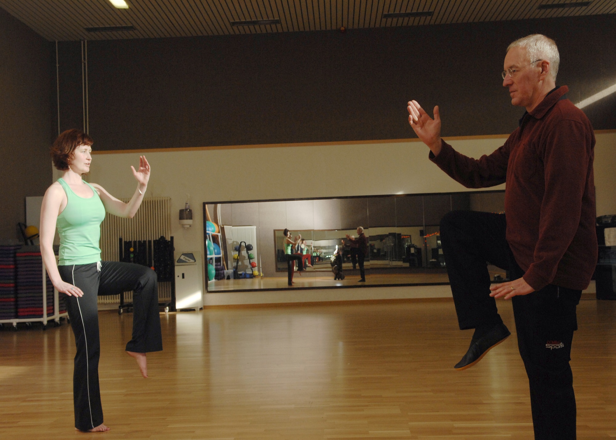 SPANGDAHLEM AIR BASE, Germany -- Colleen Colby stretches with Klaus van den Boom, Tai chi instructor, to stretch during a Tai Chi class at the Skelton Memorial Fitness Center Feb. 7, 2008. The class is intended to teach members and their dependants the basics of Tai Chi. (U.S. Air Force photo/Senior Airman Logan Tuttle)