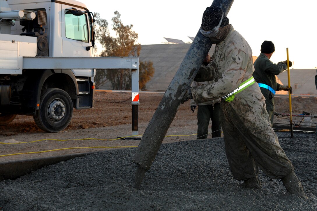 BALAD AIR BASE, Iraq -- Senior Airman Micah Shaffer, one of the 332nd Expeditionary Civil Engineer Squadron pavement and heavy equipment flight's Dirt Boyz, pours concrete onto the footer of a flightline pad here, Feb. 6. It takes about 10 truck loads of concrete to fill one 13' by 200' pad. Airman Shaffer is deployed from Ellsworth Air Force Base, S.D. (U.S. Air Force photo/ Senior Airman Julianne Showalter)