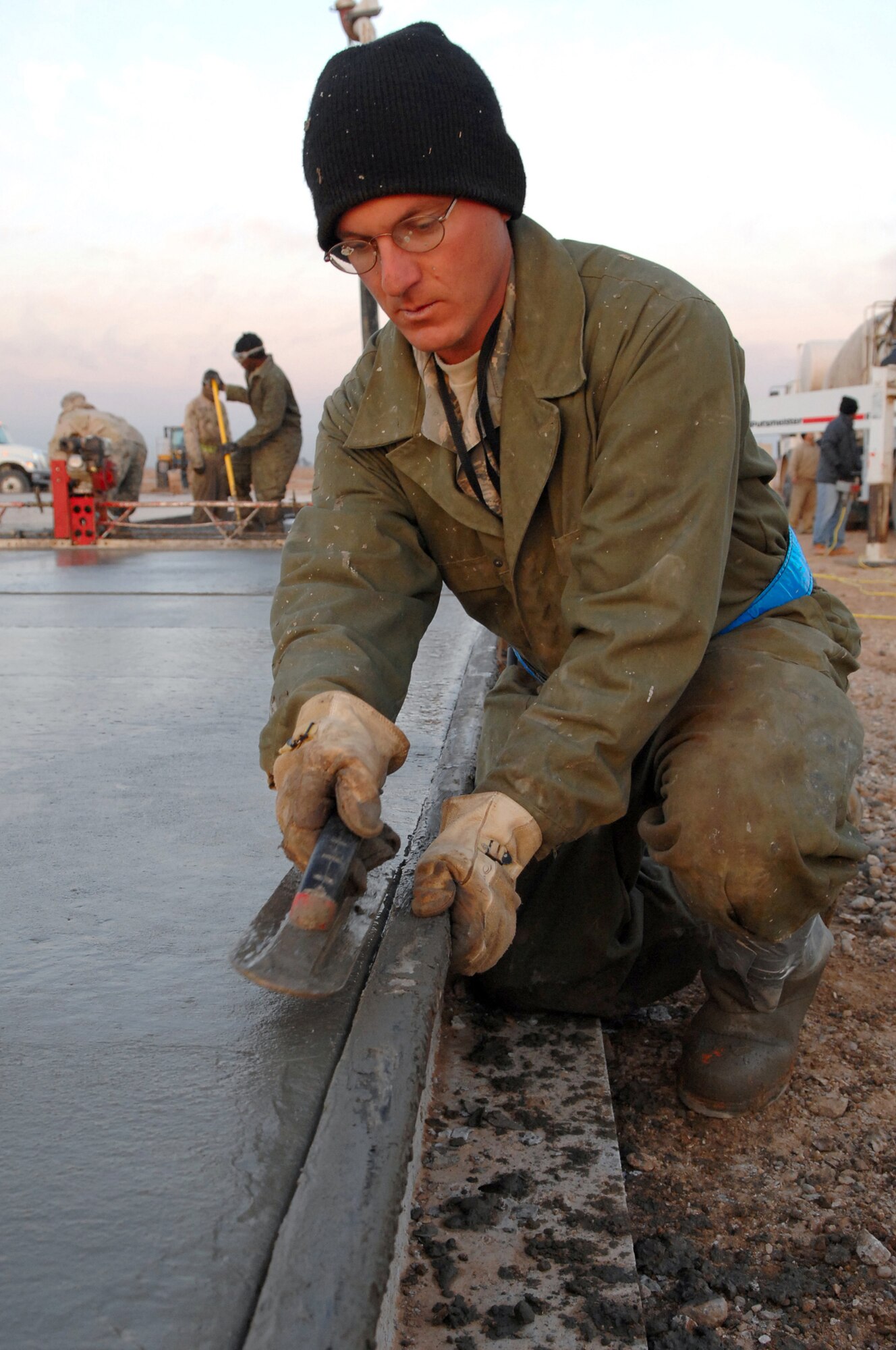 BALAD AIR BASE, Iraq -- Tech. Sgt. Jason Kerkaert, one of the 332nd Expeditionary Civil Engineer Squadron pavement and heavy equipment flight's Dirt Boyz, smoothes out the edge of a concrete pad on the flightline here, Feb. 6. The Dirt boyz, a name given to Airmen who execute concrete-related tasks, extended the pad by 10 feet to allow for more wing tip clearance during F-16 Fighting Falcon refueling efforts. Sergeant Kerkaert is deployed from Ellsworth Air Force Base, S.D. (U.S. Air Force photo/ Senior Airman Julianne Showalter)