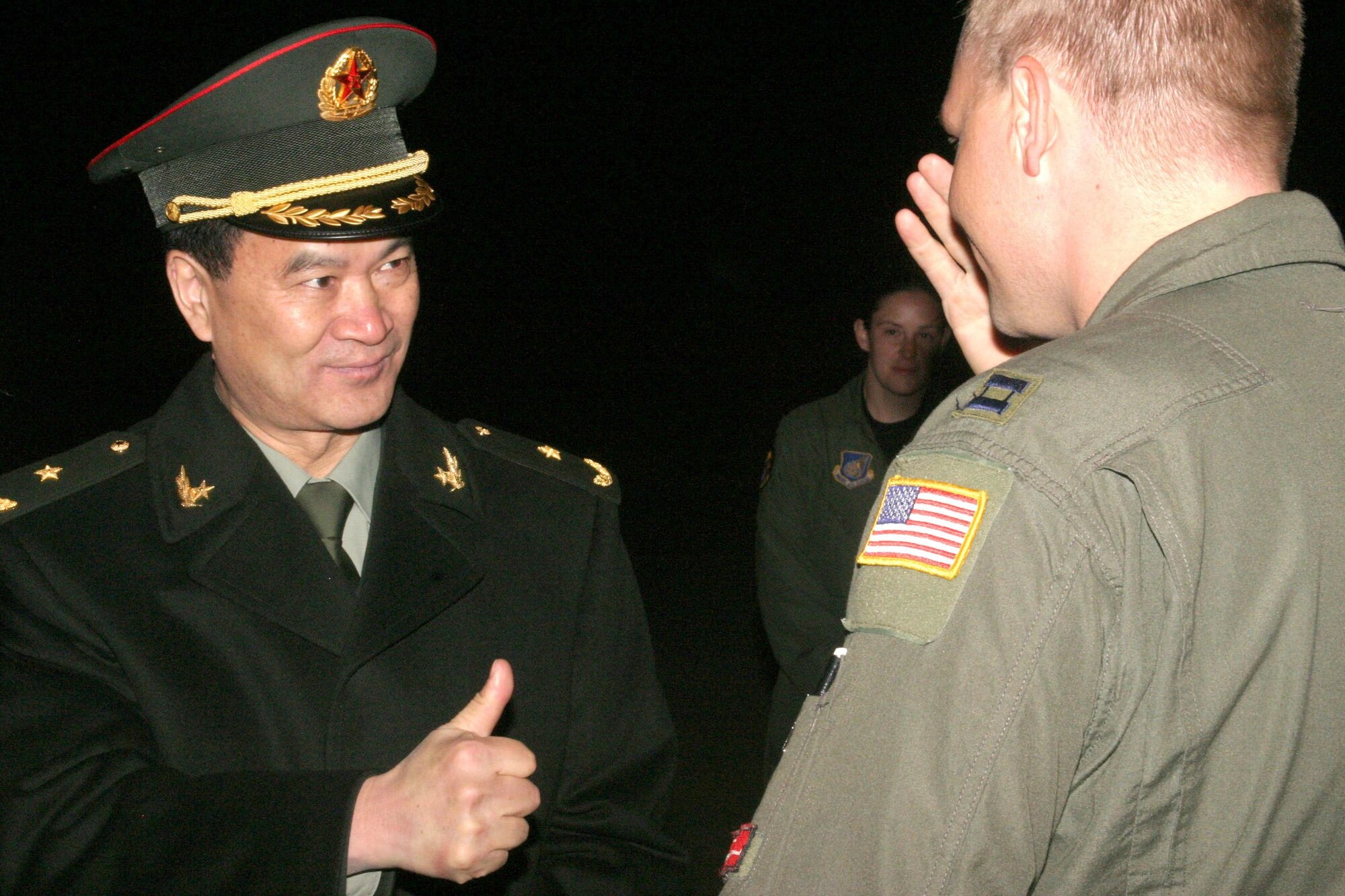 After returning a salute, Major General Lihua Qian, People?s Liberation Army, gives a thumbs-up sign to U.S. Air Force Capt. Dave Ericson, 535th Airlift Squadron, 15th Airlift Wing, Hickam Air Force Base, Hawaii. Thirteenth Air Force's 613th Air and Space Operations Center Air Mobility Divsion at Hickam AFB coordinated the delivery of 225,890 pounds of relief supplies to Shanghai within 18 hours of Secretary of Defense approval. Recently, 19 Chinese provinces experienced the most severe winter storms in 50 years, imposing severe hardships on millions of Chinese citizens. (U.S. Marine Corps photo by Cpl. Anthony J. DeCapite) 