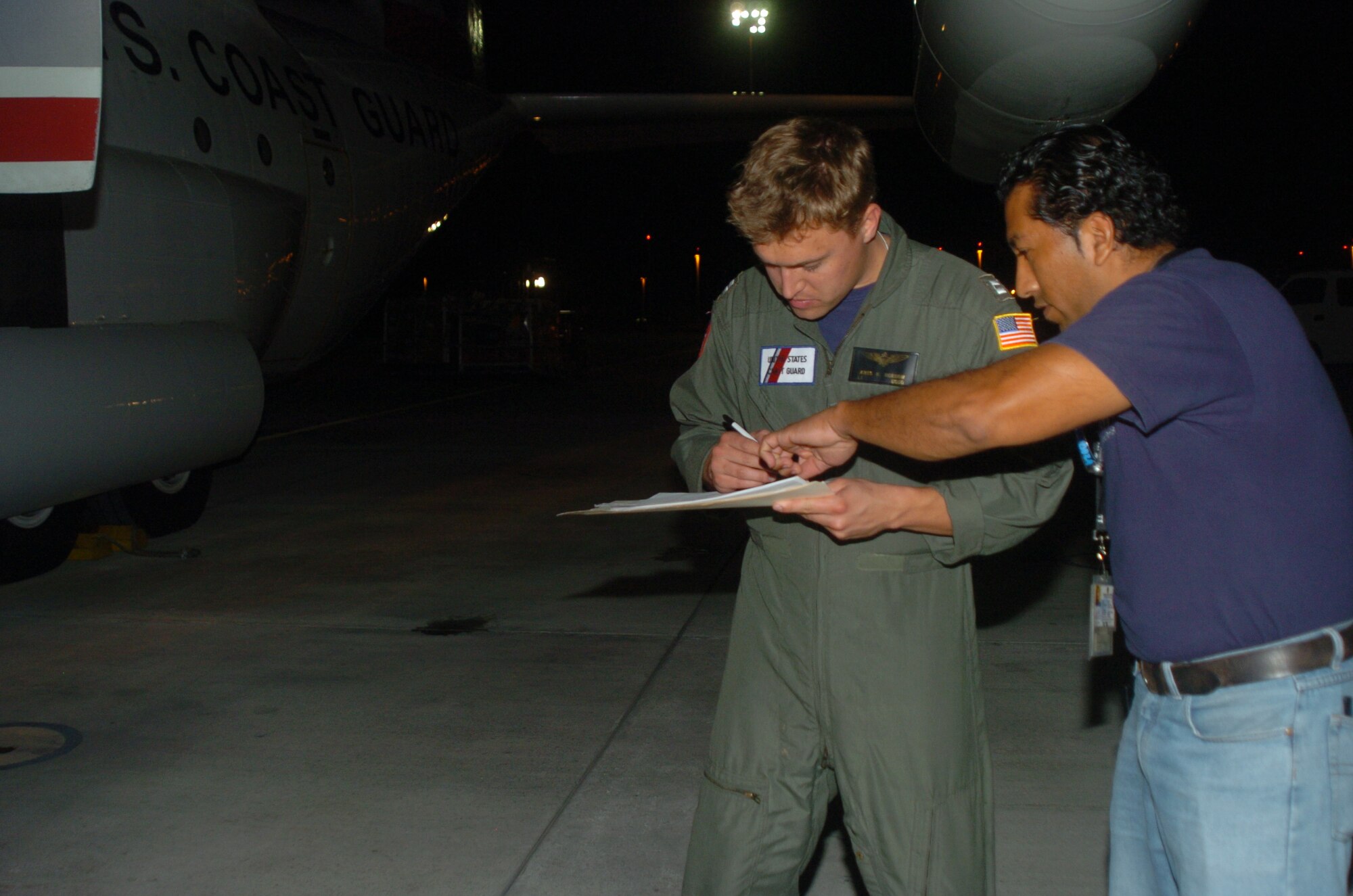 Lieutenant James K. Morrow, a member of the Coast Guard HC-130 crew, finalizes paperwork for Bolívar Nunez, a contractor for ITT Federal Services International Corporation.  LT Morrow was on the HC-130 Hercules that carried more than one million vitamins and a generator for donation by a non-profit organization to local schools and orphanages in Ecuador.  The Coast Guard crew is deployed to Forward Operating Location, Manta, Ecuador from Air Station Clearwater, Fla.  (U.S. Air Force photo/Capt. Ashley Norris)
