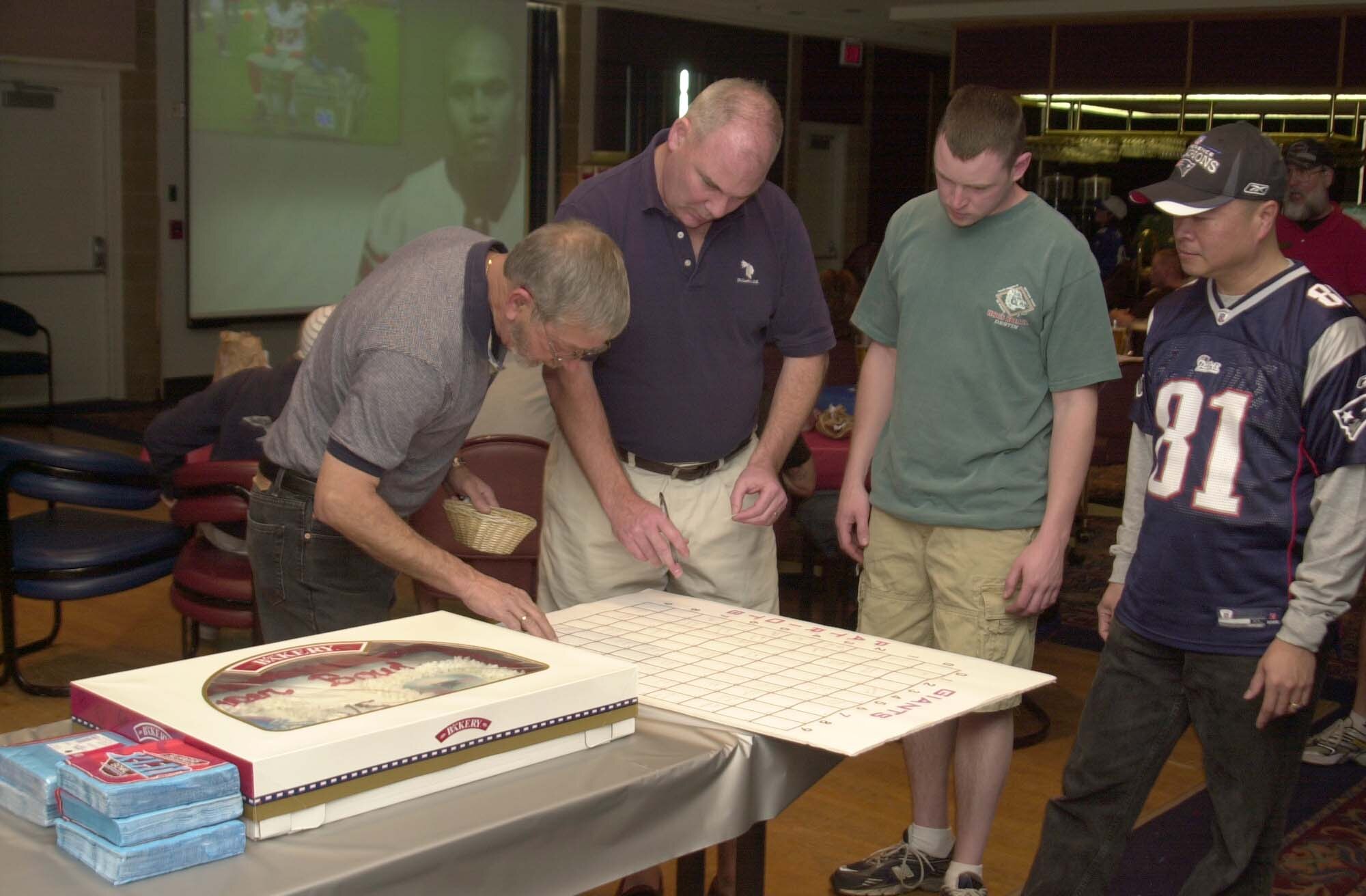 Far left: Ray Kazura, Event Center manager, explains the rules of a football game pool to Super Bowl party guests Feb. 3. Guests were invited to play the pool with no fees. (U.S. Air Force photo by Senior Airman Luis Loza Gutierrez)