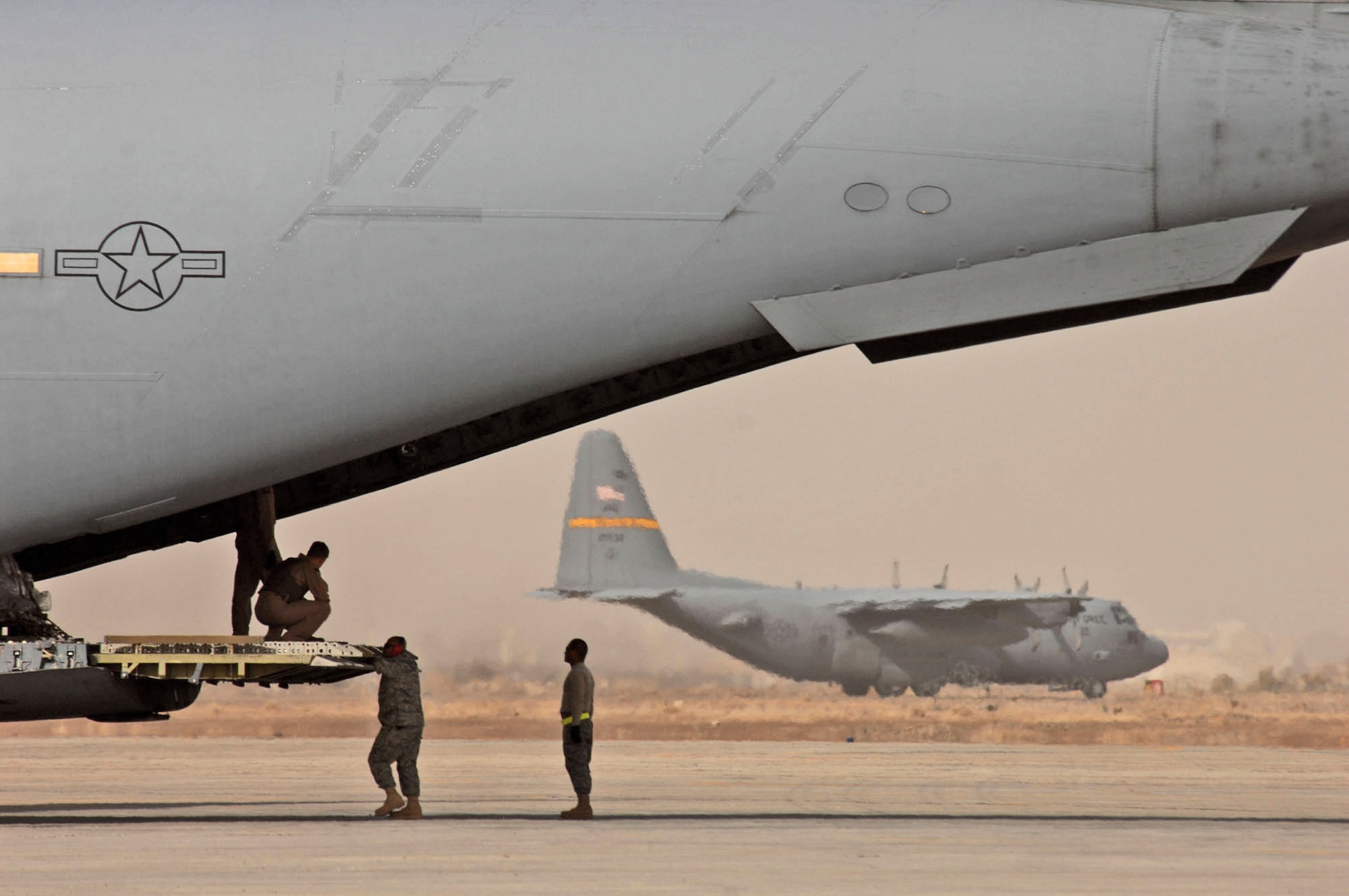 Airmen wait for a pallet of equipment to be loaded on a C-17 Globemaster III Jan. 30 at Sather Air Base, Iraq.  The largest number of passengers and the second largest amount of cargo in Iraq moves through Sather AB. (U.S. Air Force photo/Tech. Sgt. Jeffrey Allen)
