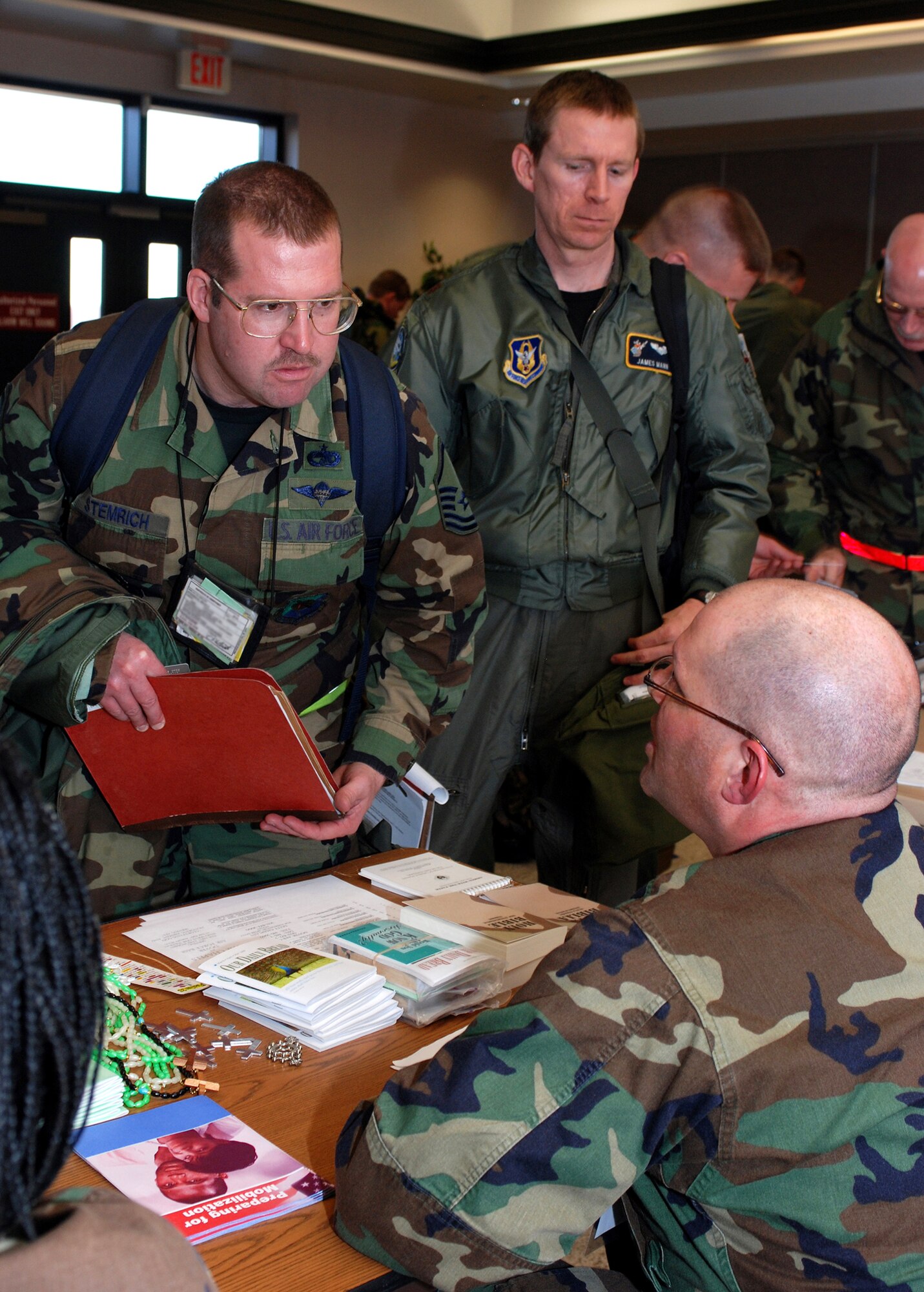 DOVER AIR FORCE BASE, Del. -- 512th Airlift Wing Chaplain (Capt.) Mark Kelleher, explains to Master Sgt. Brad Stemrich, 46th Aerial Port Squadron (left) and Maj. James Mann, 709th Airlift Squadron, the different services chaplains offer to deploying Airmen. Both 436th and 512th Airlift Wing members participated in a deployment exercise Feb. 2.  During the exercise, members were evaluated in several areas, including processing through a deployment line, as seen here. The exercise was held in preparation for the Operational Readiness Inspection to be held this summer. (U.S. Air Force photo by Staff Sgt. Steve Lewis)