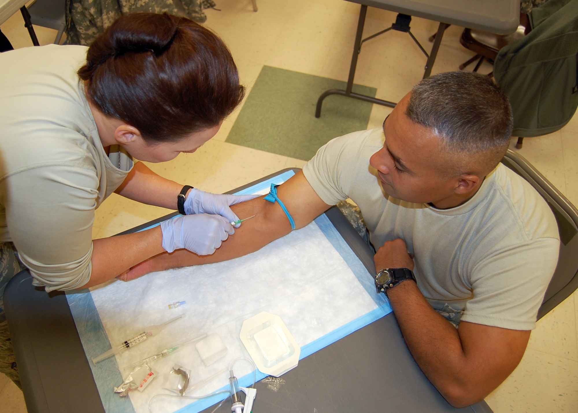 Tech. Sgt. Hattie Douglas performs a saline lock on Army Maj. Jesus Rodriguez. Sergeant Douglas, deployed from Detachment 030, Air Force Reserve Officer Training Corps at the University of Arkansas, is serving as Provincial Reconstruction Team Gardez’ personnelist. Current combat zone medical protocol calls for administering a saline lock (more commonly known as an IV) to combat casualties because it’s easier to accomplish while veins are still viable rather than later when time might be short and the veins collapsed from blood loss. (U.S. Air Force photo/Capt. Ken Hall)