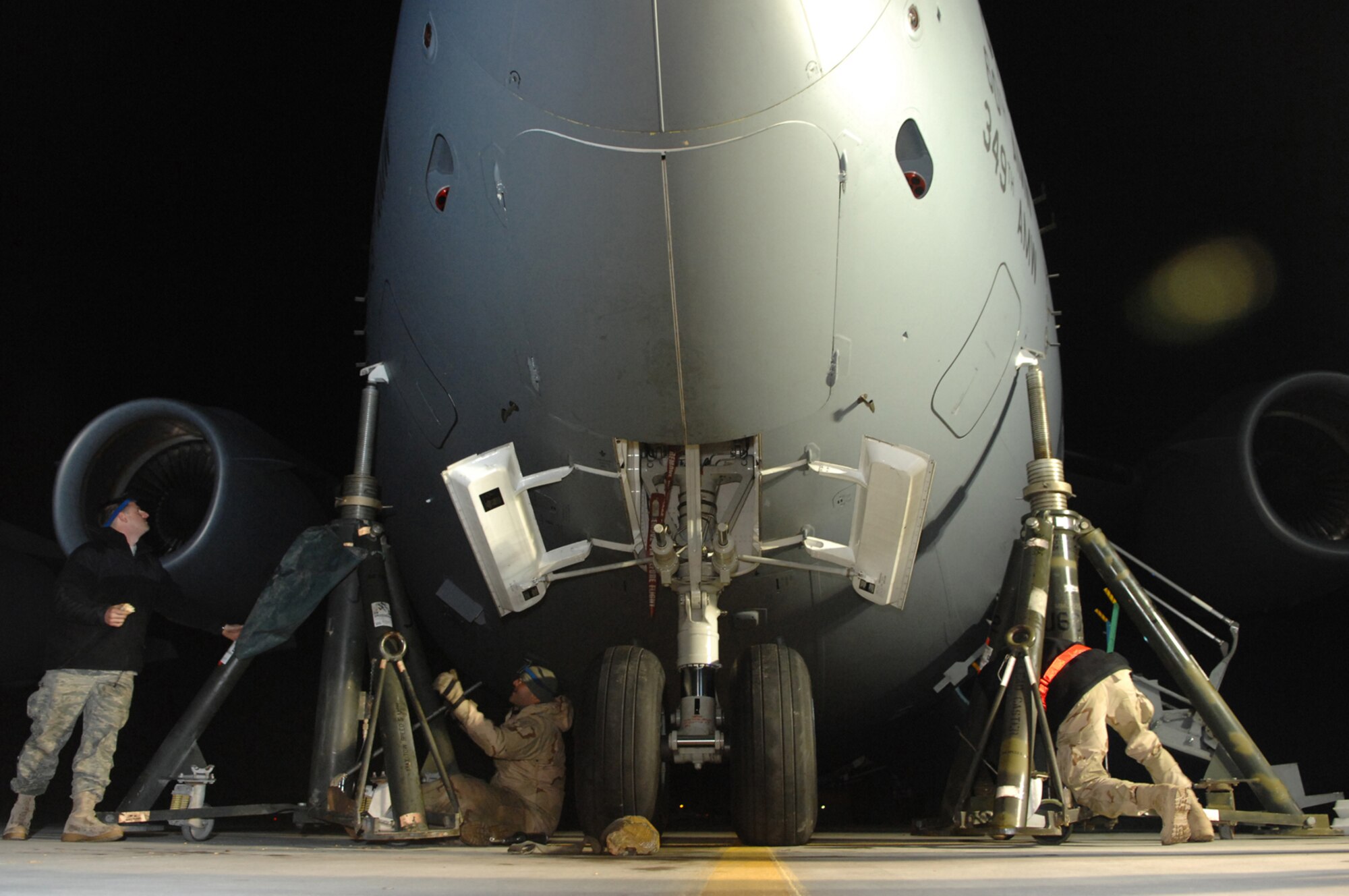 BALAD AIR BASE, Iraq -- Crew chiefs from the 721st Air Mobility Maintenance Group Detachment 5, raise a C-17 for a final operations test on the nose landing gear strut assembly here, Feb. 8. Before putting the aircraft back into operational status the crew chiefs must perform landing procedures from the cockpit. (U.S. Air Force photo/ Senior Airman Julianne Showalter)