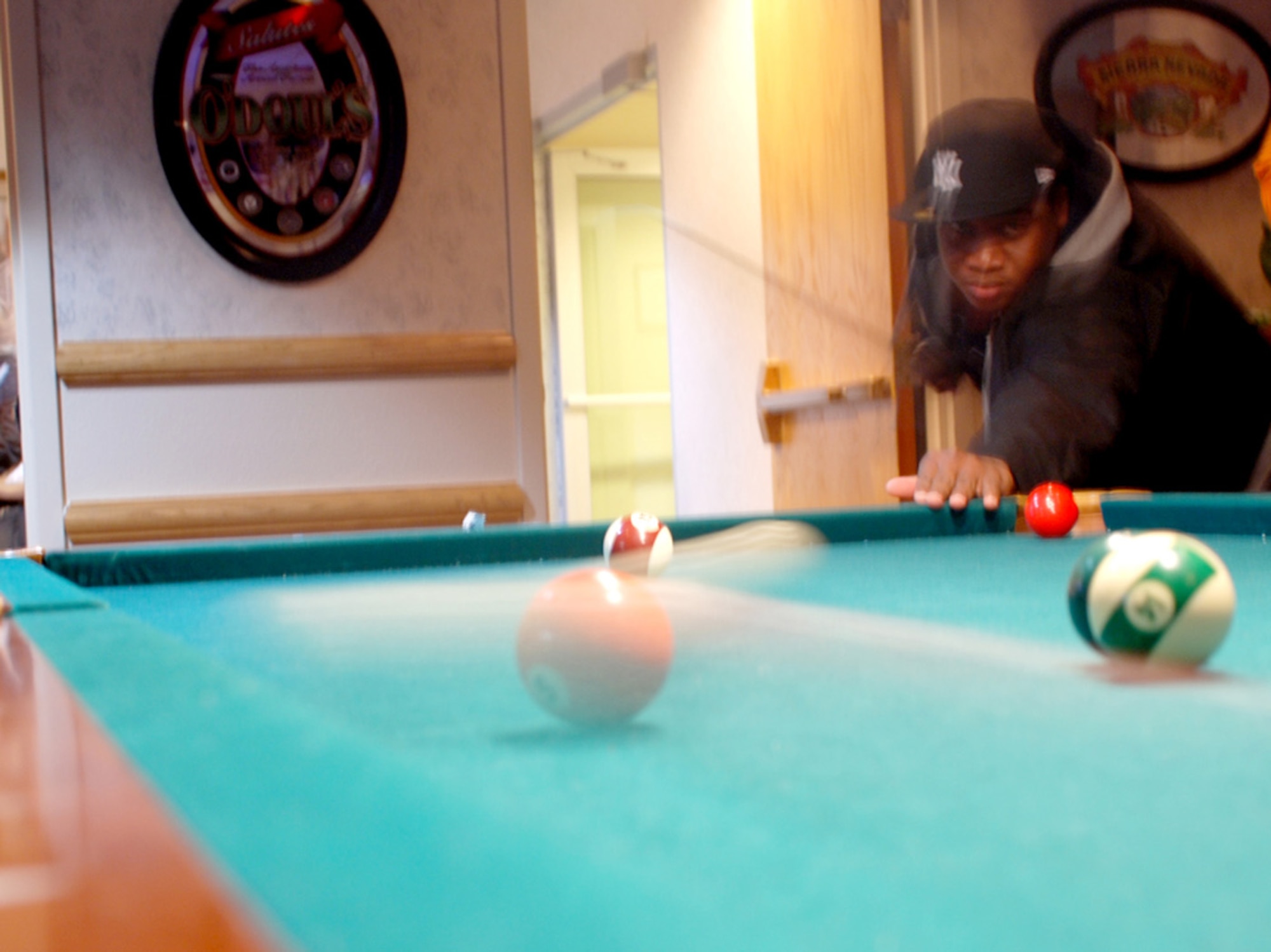 An Airman shoots the cue ball toward the five ball during a game of pool at the Mardi Gras event. Along with the main events, party goers could sit and relax in the bar area or play a casual game of pool.