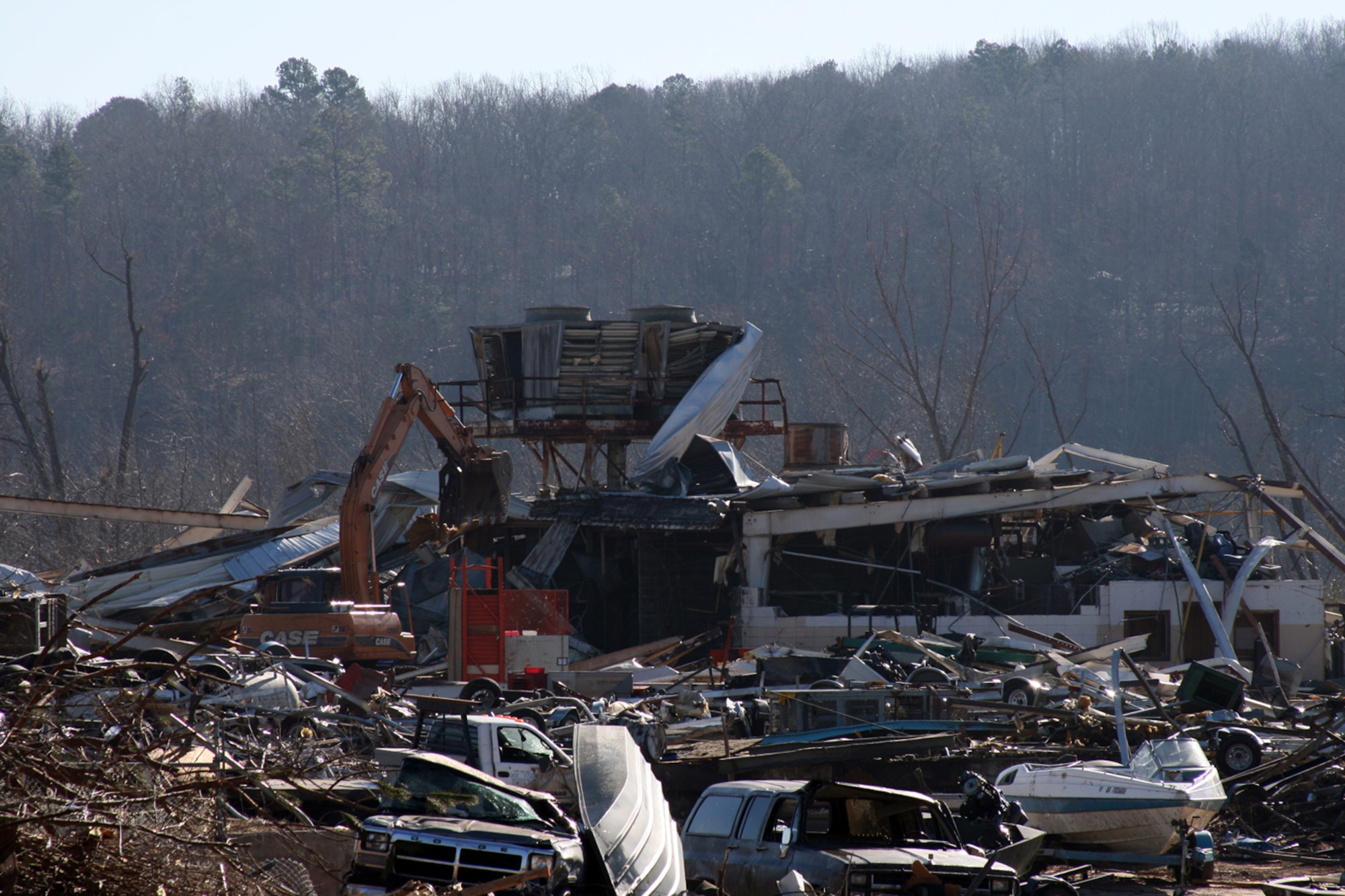 Volunteers and workers clear debris at the Clinton, Ark., boat factory Feb. 9. One person at the factory died when a tornado struck the factory Feb. 5. The EF4 tornado, measured on the Enhanced Fujita scale, had winds of 166-200 mph as it ripped a 123-mile path through North Central Arkansas. About 50 Arkansas Army and Air National Guard Soldiers and Airmen are helping provide security in Clinton and Van Buren County. Arkansas National Guard officials expect them to be in the area for about a week. (U.S. Air Force Photo by Master Sgt. Bob Oldham)