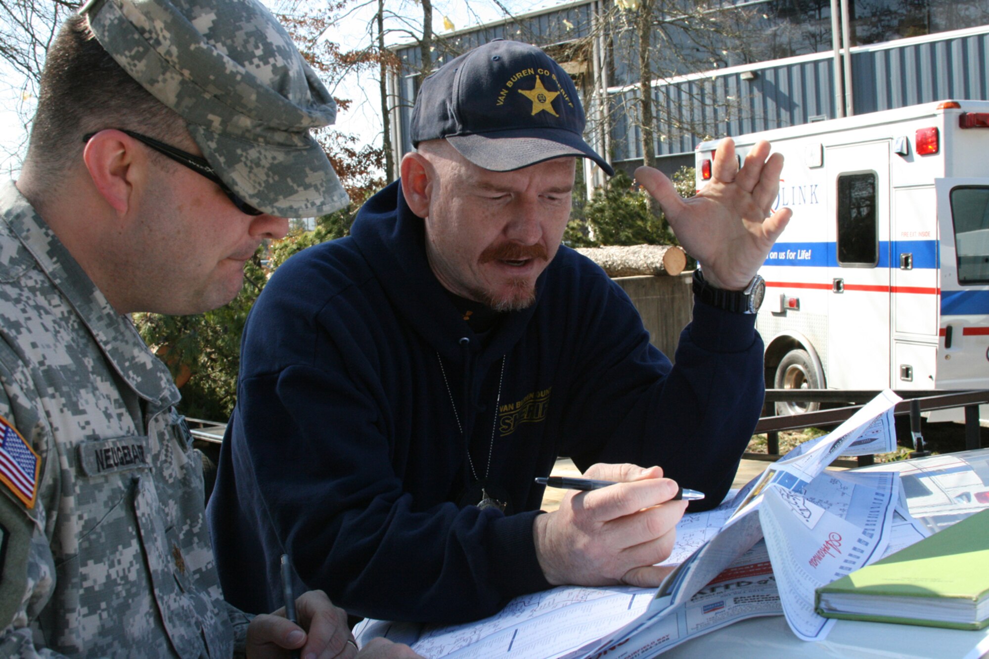 Arkansas Army Guard Maj. Derald Neugebauer, a law enforcement coordinator assigned to assist  Van Buren County officials, discusses security requirements Feb. 9 with Van Buren County Sheriff's Lt. Wesley Potts. An EF4 tornado, measured on the Enhanced Fujita scale, had winds of 166-200 mph as it ripped a 123-mile path through North Central Arkansas. About 50 Arkansas Army and Air National Guard Soldiers and Airmen are helping provide security in Clinton and Van Buren County. Arkansas National Guard officials expect them to be in the area for about a week. (U.S. Air Force Photo by Master Sgt. Bob Oldham)