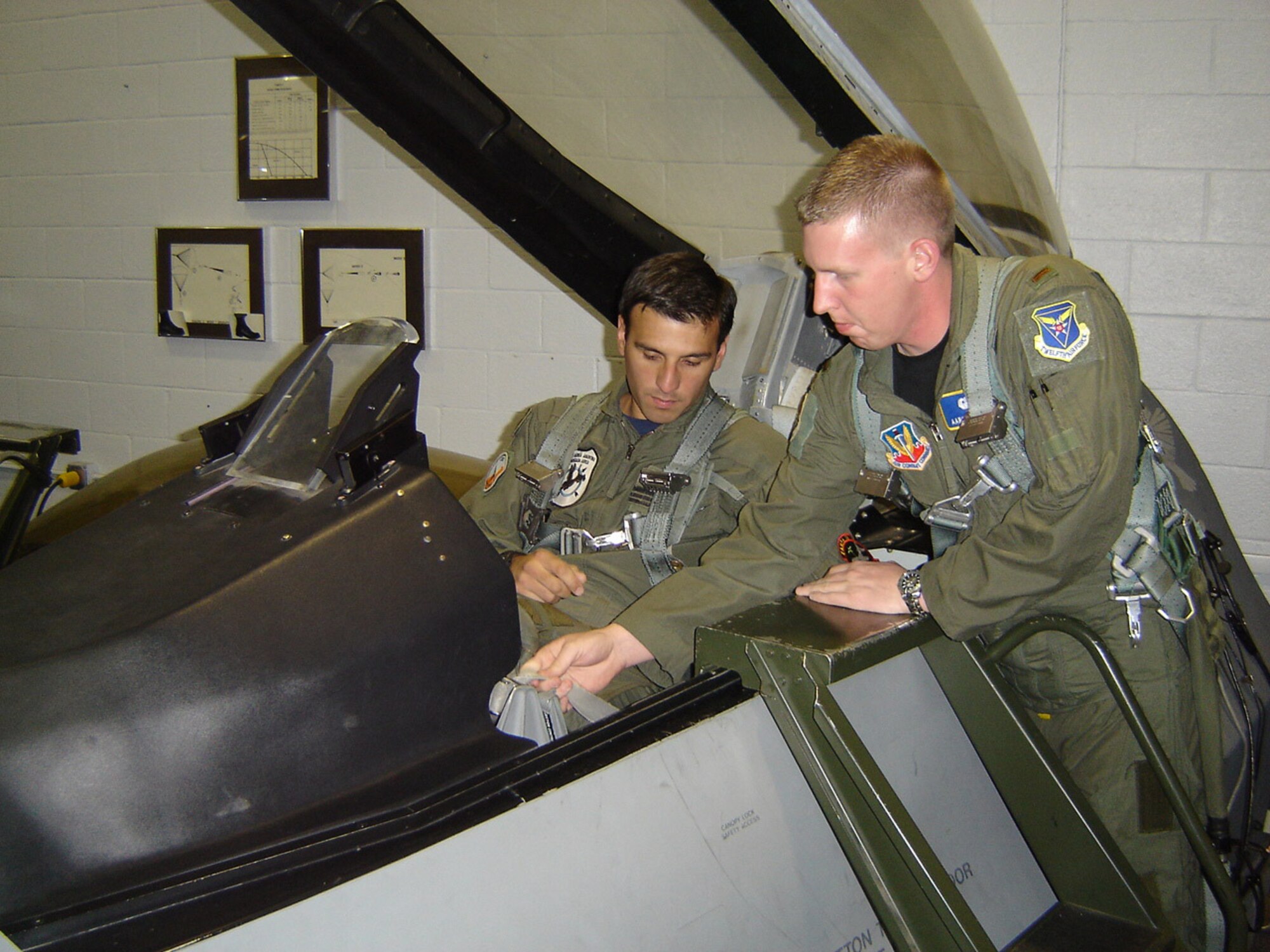 Lt. Aaron Schuett, a Desk Officer with 12th Air Force (Air Forces Southern), trains Capt. Carlos Martin, a member of the Argentine Air Force, in proper F-16 Fighter Falcon ejection procedures at Luke Air Force Base, Ariz. prior to his F-16 training mission. Captain Martin visited the United States to participate in a joint subject matter expert exchange program where he trained alongside U.S. Airmen in fighter operations Jan. 21-25.