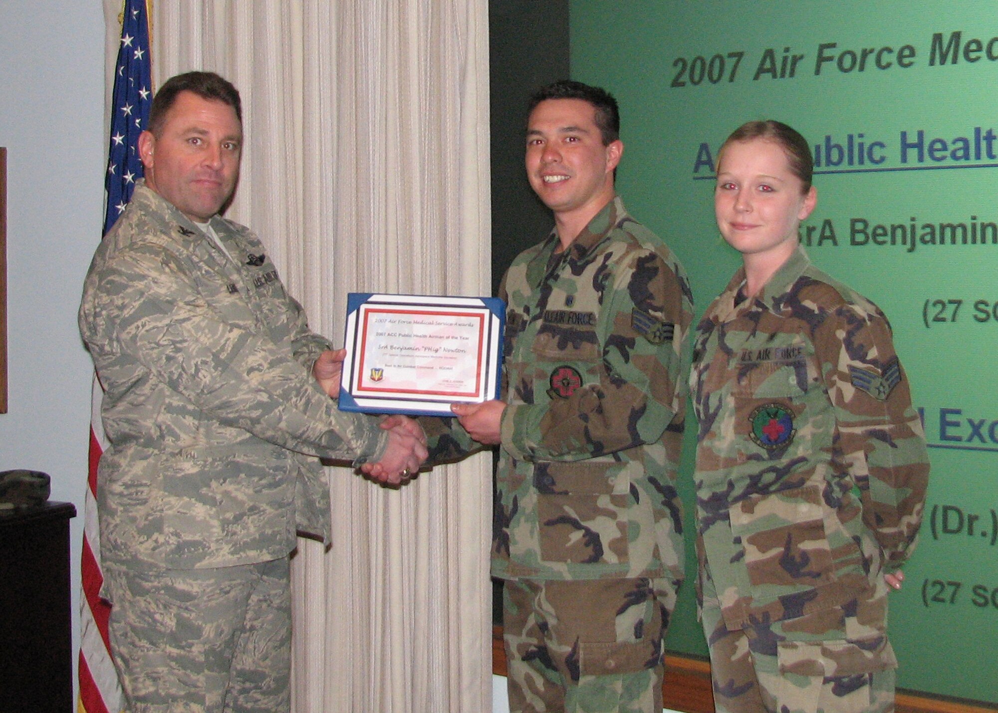 CANNON AIR FORCE BASE, N.M. -- Colonel Timothy Leahy, 27th Special Operations Wing commander, presents the 2007 Air Combat Command  Public Health  Airman of the Year award to Senior Airman Benjamin Newton on Feb. 5. Airman Newton  is accompanied by his wife, Senior Airman Ashley Newton, and both are assigned to 27th Special Operations Aeromedical  Dental Squadron. (US Air Force photo by Master Sgt. Cynthia Crouch)  