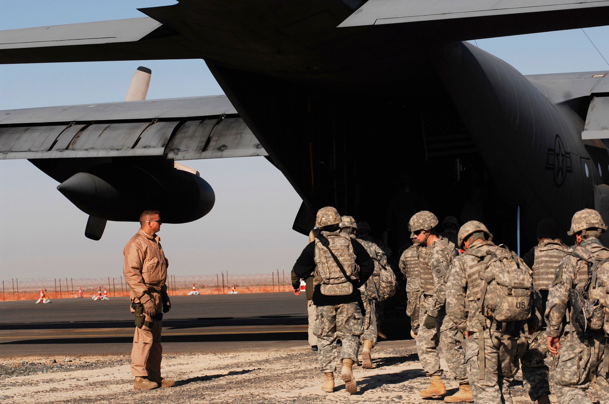 Soldiers board an Air Force C-130 Hercules as Senior Airman Kenny Harmon watches Feb. 4 at a Southwest Asia air base. Airman Harmon, a 737th Expeditionary Airlift Squadron C-130 loadmaster, ensures the safety of boarding passengers being transported throughout the area of responsibility in support of operations Enduring Freedom and Iraqi Freedom. (U.S. Air Force photo/Staff Sgt. Patrick Dixon)
