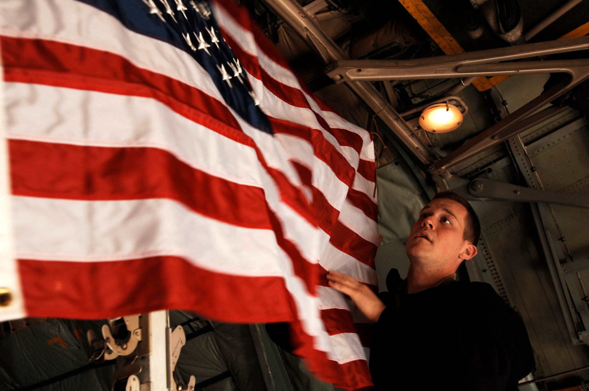 1st Lt. Matthew Macfarlane hangs up an American flag in the cargo area of a C-130 Hercules prior to takeoff of a mission Feb. 4 at a Southwest Asia air base. The flag belongs to one of Lieutenant Macfarlane's ROTC instructors and will be displayed while flying over Iraq on a mission in support of Operation Iraqi Freedom. Lieutenant Macfarlane is a C-130 pilot deployed with the 737th Expeditionary Airlift Squadron. (U.S. Air Force photo/Staff Sgt. Patrick Dixon)
