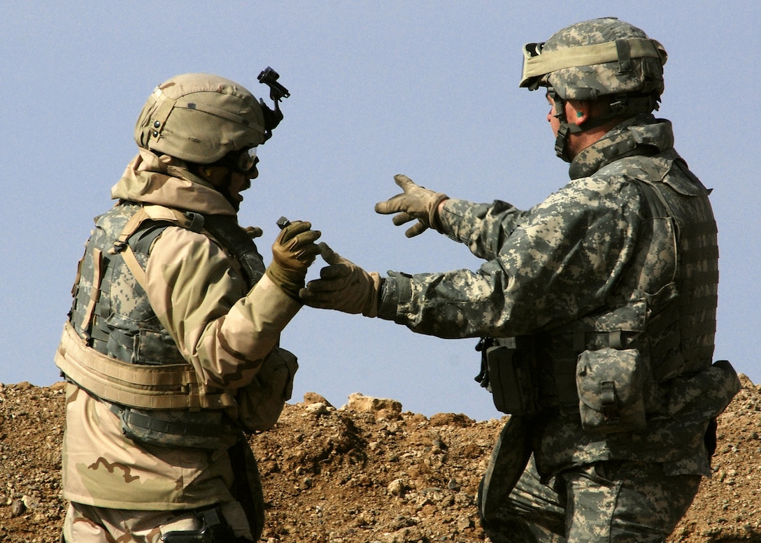 Army Sgt. 1st Class Brian Simmons directs Navy Petty Officer 2nd Class David Crabb, of Navy Embedded Training Team 3-205th Garrison, on where to throw a hand grenade during weapons familiarization training. Simmons and Crabb practiced throwing grenades, which Crabb had never done before. Both work out of Forward Operating Base Tombstone, in Afghanistan’s Helmand province. Photo by Petty Officer 1st Class David M. Votroubek, USN 