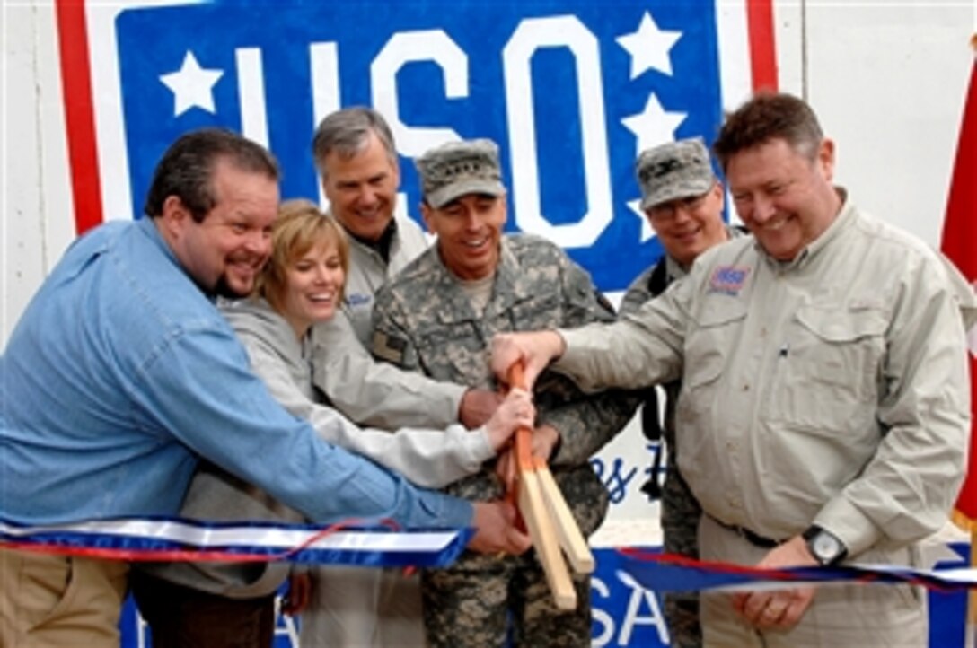 U.S. Army Gen. David Petraeus, the commanding general of Multinational Force - Iraq, center, Ned Powell, USO Worldwide president and CEO, left center, and other USO personnel cut a ceremonial ribbon at Balad Air Base, Iraq, Feb. 7, 2008, during the opening ceremony for the first USO in Iraq.