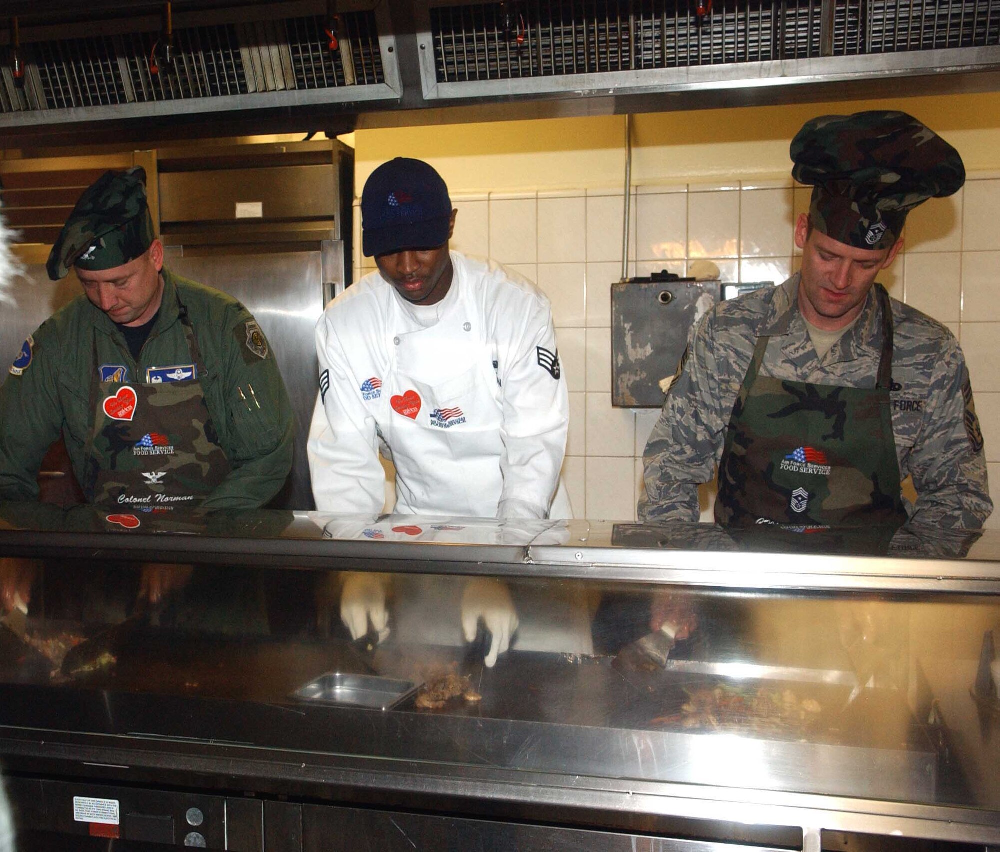 (From left to right) Col. Jon Norman, 51st Fighter Wing commander, Senior Airman Antwon Nixon, 51st Services Squadron, and Chief Master Sgt. Darrin Dwyer, 51st FW command chief, cook Mongolian barbecue Feb. 12 at the Pacific House Dining Facility. The special meal, part of 51st SVS’ “Feeding the Force” campaign, was designed to increase morale and customer satisfaction.  (U.S. Air Force photo/Staff Sgt. Candy Knight)