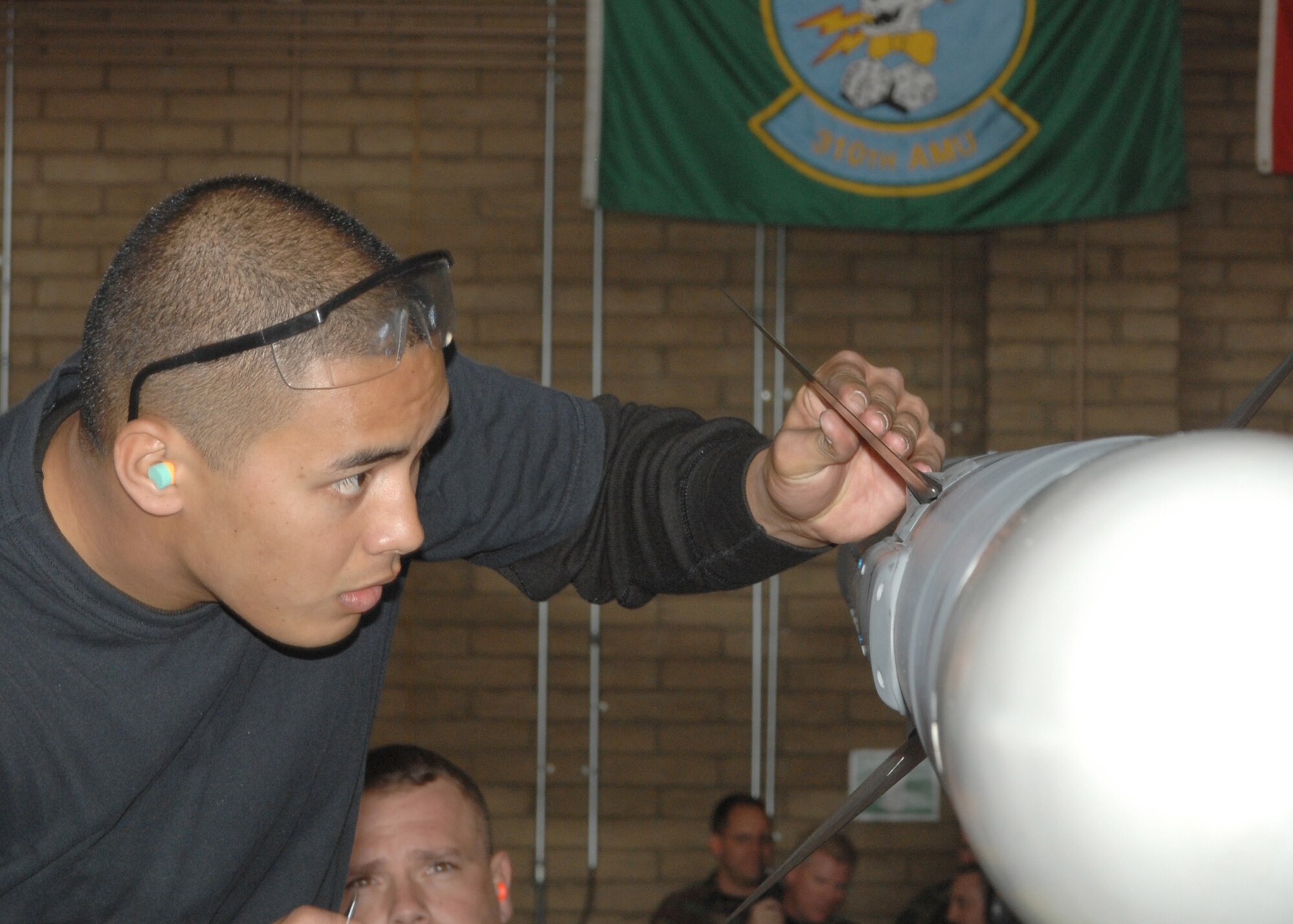 Senior Airman Treston Kaneao from the 61st Aircraft Maintenance Unit aligns the fins on a AIM-120 missile during the Weapons Load Crew Competition here at Luke on Feb 8. The 310th AMU crew 16 beat out the 61st AMU crew M80 during the competition. (photo by Tech. Sgt. Raheem Moore)
