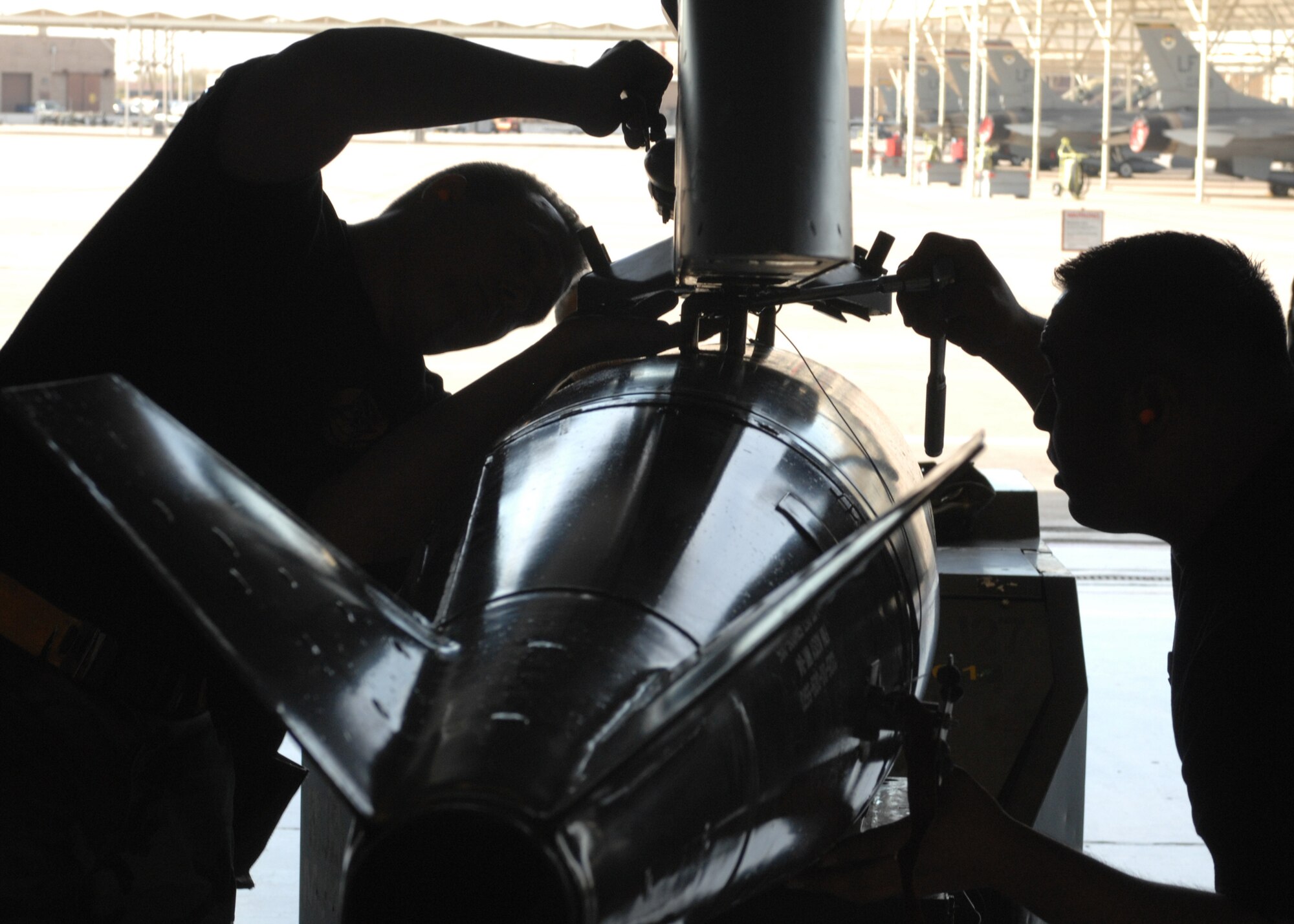 Staff Sgt. Stephen Waide (left) and Senior Airman Hector Miranda from the 61st Aircraft Maintenance Unit secures a MK-84LD bomb onto a F-16 during the Weapons Load Crew Competition here at Luke on Feb 8. The 62nd AMU crew 202 beat out the 61st AMU crew 74 during the competion. (photo by Tech. Sgt. Raheem Moore)