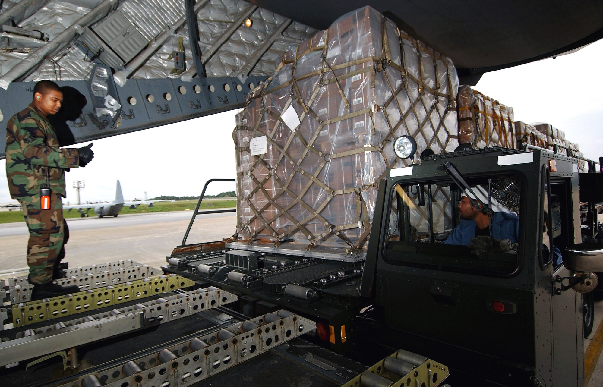 Senior Airman William Judge guides cargo pallets onto a C-17 Globemaster III from Elmendorf Air Force Base, Alaska, Feb. 8 at Kadena Air Base, Okinawa. Members of the 733rd Air Mobility Squadron loaded medical supplies, food rations and cold weather gear onto this C-17 and another from Hickam Air Force Base, Hawaii, bound for China as part of a humanitarian relief effort. Airman Judge is an air transportation specialist. (U.S. Air Force photo/Tech. Sgt. Rey Ramon)