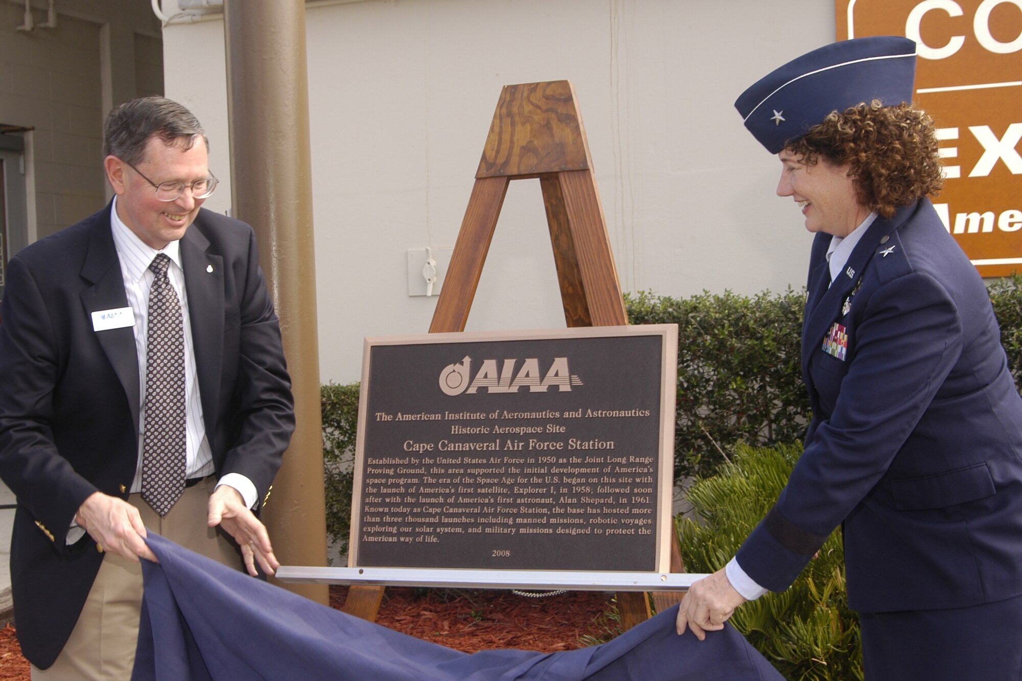 Retired Air Force Maj. Gen. Bob Dickman, executive director of the American Institute of Aeronautics and Astronautics, and Brig. Gen. Susan Helms, 45th Space Wing commander, unveil a marker designating Cape Canaveral AFS as a Historic Aerospace Site. (U.S. Air Force photo by Regina Mitchell-Ryall)