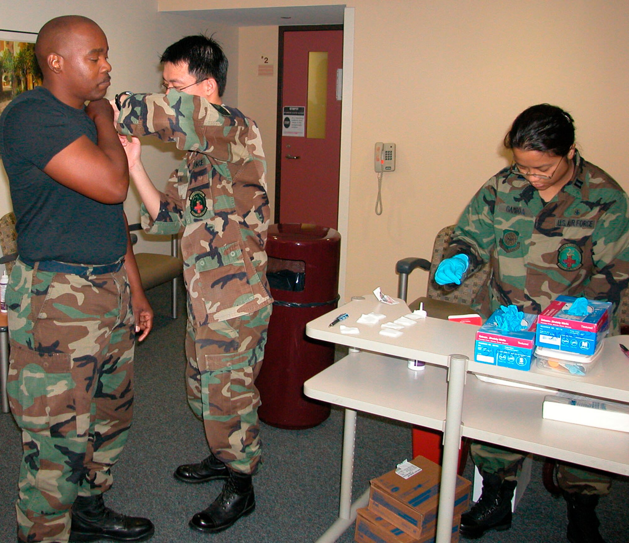 Technical Sgt. Eddie Leung of the 349th Medical Squadron administers the flu shot to a fellow reservist recently during a Unit Training Assembly while Captain Emily B. Gamboa of the 349th Medical Squadron prepares supplies for the patient line of reservists. (U.S. Air Force photo/Technical Sgt. Mary Beth Bemis)