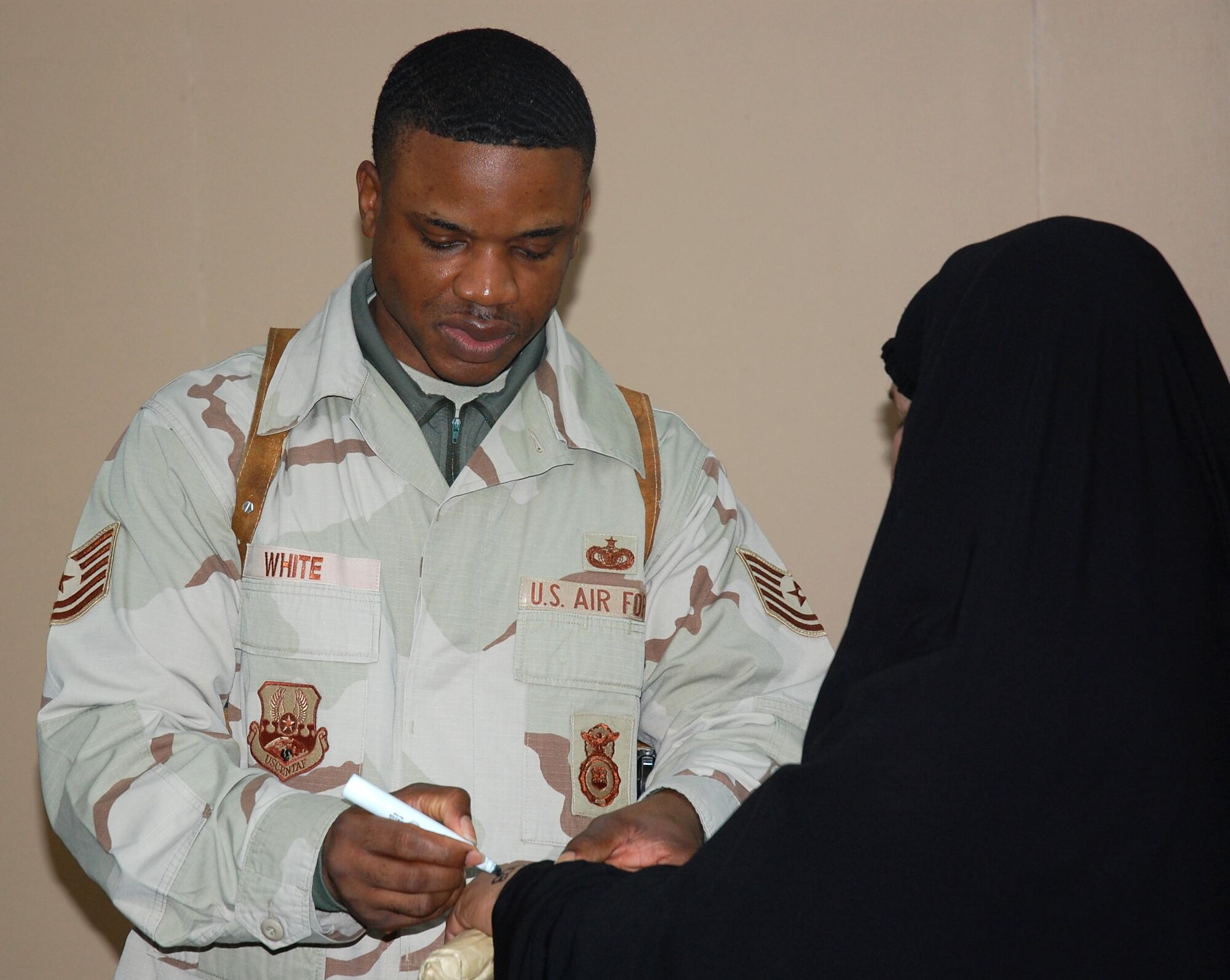 Tech. Sgt. Mario White processes an Iraqi woman visiting a family member Feb 10 detained in the Theater Internment Facility at Camp Bucca, Iraq. Airmen deployed to the 886th ESFS operate the TIF's vigorous visitation program which houses detainees determined to be a security threat against Iraqi citizens or coalition forces. More than 1,700 friends and family members visit the detainees each week. Sergeant White is an 886th Expeditionary Security Forces Squadron deployed from Royal Air Force Lakenheath, England. (U.S. Air Force photo/Capt. Jason McCree) 