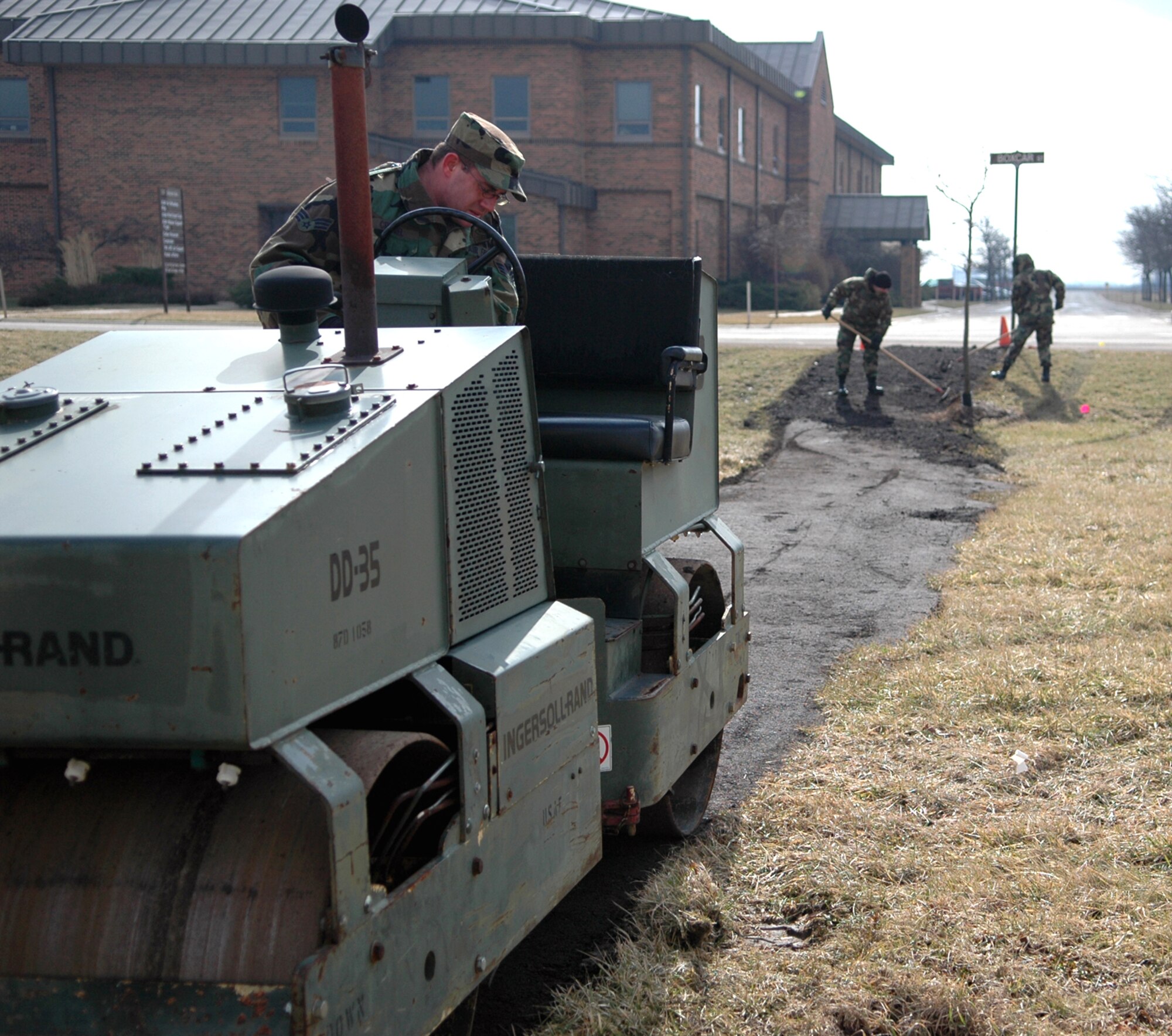 GRISSOM AIR RESERVE BASE, Ind.,-- Members of the 434th Civil Engineers Squadron install a temporary walkway for a flag pole being located on the north end of Bldg. 596. Senior Airman Sam Siemons, an equipment specialist, operates a vibratory roller, while Staff Sgt. John Hurt, job supervisor, and Senior Airman Philip Budnick, a civil engineering specialist, smooth out the temporary walkway during the February unit training assembly.   (U.S. Air Force photo/Senior Airman Carl Berry)