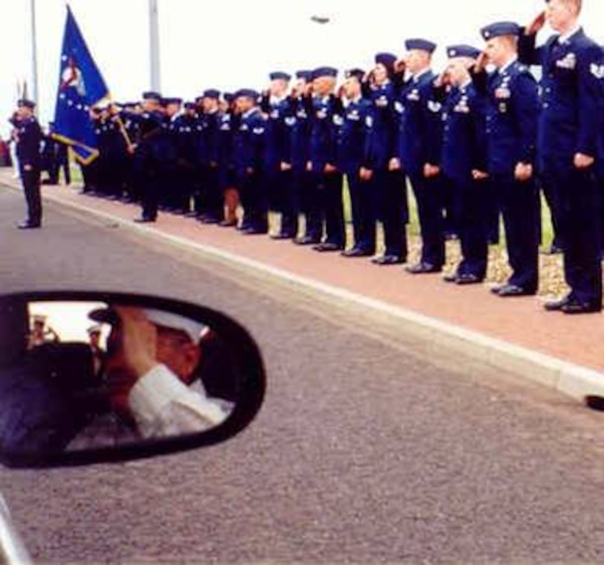 Dr. Robert L. Johnson who 56 years earlier had been on duty in the Molesworth Tower the night his base was bombed, is shown reflected in the mirror of a car as he and other 303rd Bomb Group (Heavy) Veterans arrive for the Group's "365th Mission" in June2000.  (Photo courtesy 303rd Bomb Group and Mary Johnson Hemminger)