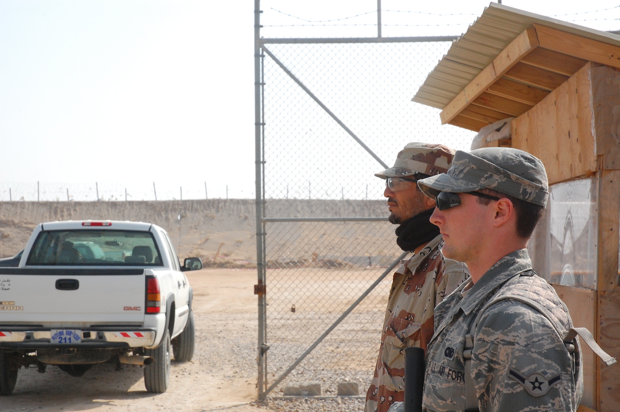 CAMP BUCCA, Iraq – Airman Mikel Whited, 886th Expeditionary Security Forces Squadron, and an Iraqi Correctional Officer stand guard outside the Theater Internment Facility in Camp Bucca, Iraq, Feb. 10, 2008.  Approximately 1,000 ICOs work side-by-side Airmen, Sailors and Soldiers guarding detainees at the TIF housing detainees determined to be a security threat against Iraqi citizens or coalition forces. Airman Whited is deployed from Eielson Air Force Base, Alaska. (U.S. Air Force Photo/Capt. Jason McCree)