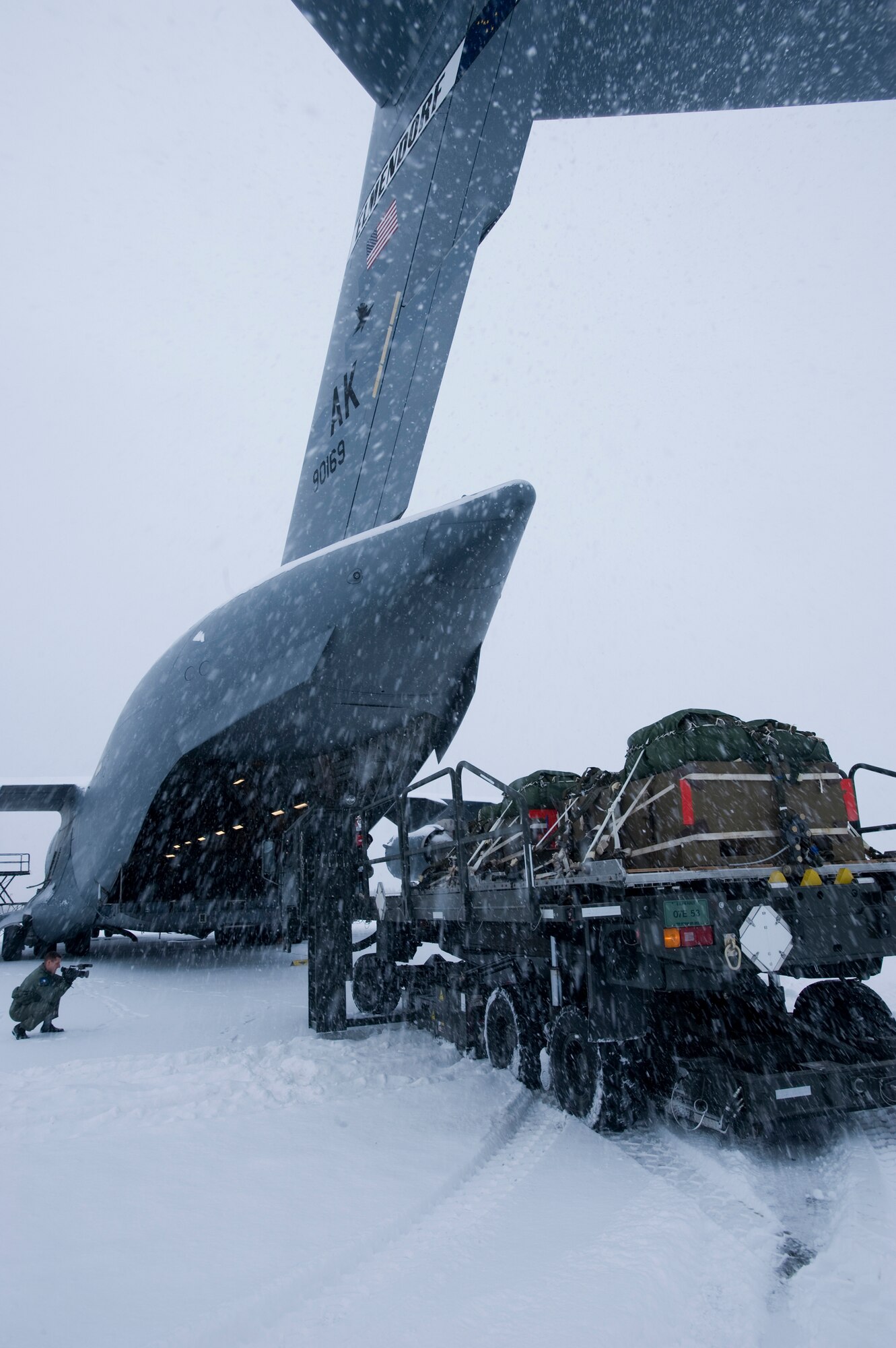 ELMENDORF AIR FORCE BASE, Alaska -- A cargo loader trudges through heavy snow to deliver cargo bundles to a C-17 Globemaster III from the 517th Airlift Squadron before a training mission here. The training mission included dropping Army Airborne Soldiers from Fort Richardson, Alaska and conducting air drops of training bundles that simulate the Soldier's equipment. (U.S. Air Force photo by Master Sgt. Keith Brown)