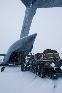 A cargo loader trudges through heavy snow to deliver cargo bundles to a C-17 Globemaster III from the 517th Airlift Squadron before a training mission here. The training mission included dropping Army Airborne Soldiers from Fort Richardson, Alaska and conducting air drops of training bundles that simulate the Soldier's equipment. (U.S. Air Force photo/Master Sgt. Keith Brown) 
