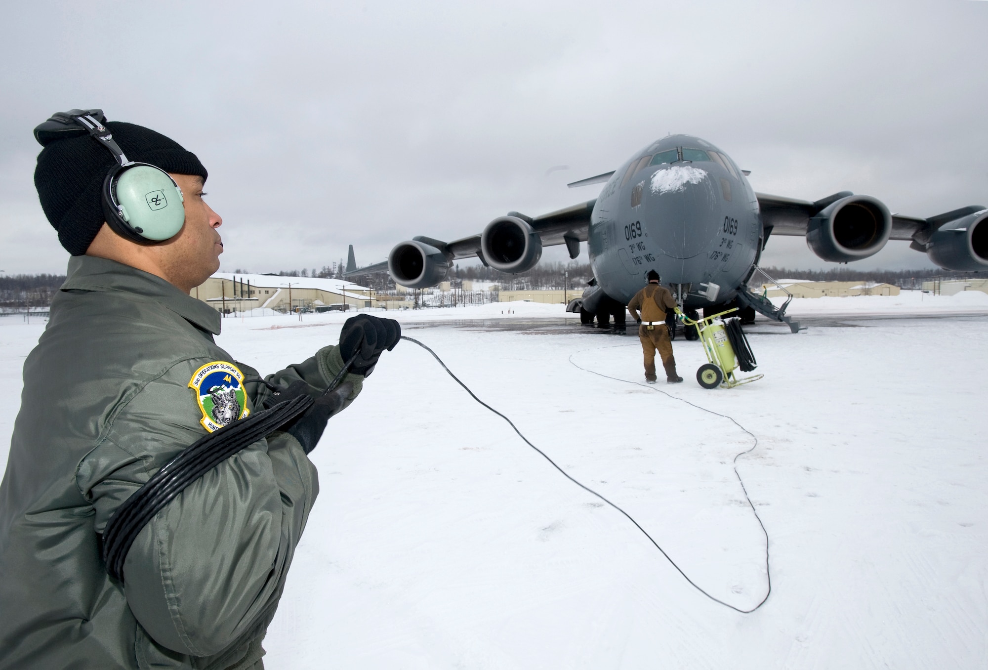 ELMENDORF AIR FORCE BASE, Alaska -- Staff Sgt. Bryan Amaya, a C-17 Globemaster III loadmaster from the 517th Airlift Squadron, wraps up a communication cord after monitoring engine start up before a training mission. The training mission included dropping Army Airborne Soldiers from Fort Richardson, Alaska, and conducting air drops of training bundles that simulate the Soldier's equipment. (U.S. Air Force photo by Master Sgt. Keith Brown)